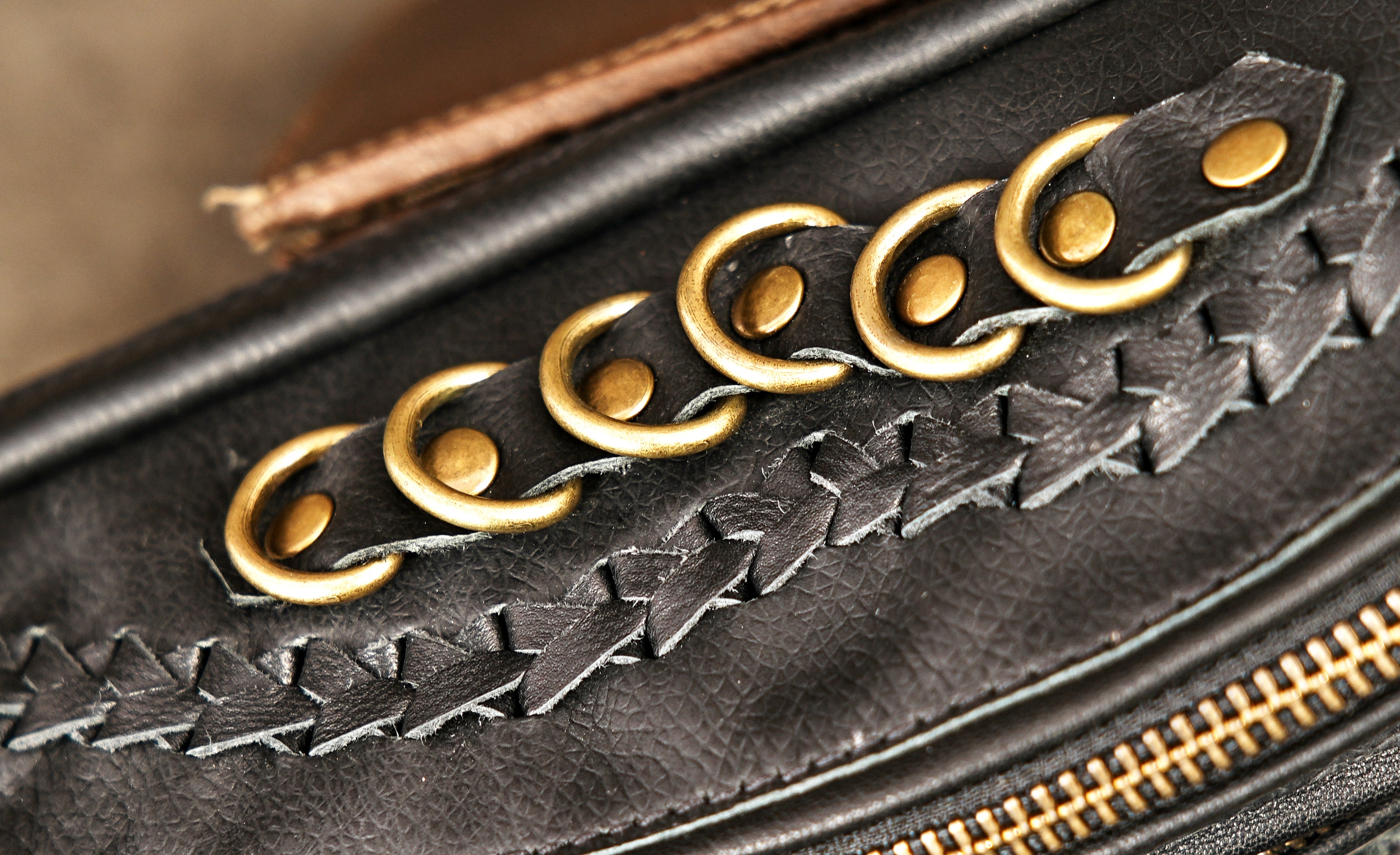 Crossbody or waist-wearable black leather festival bag with gold studded patchwork design.
