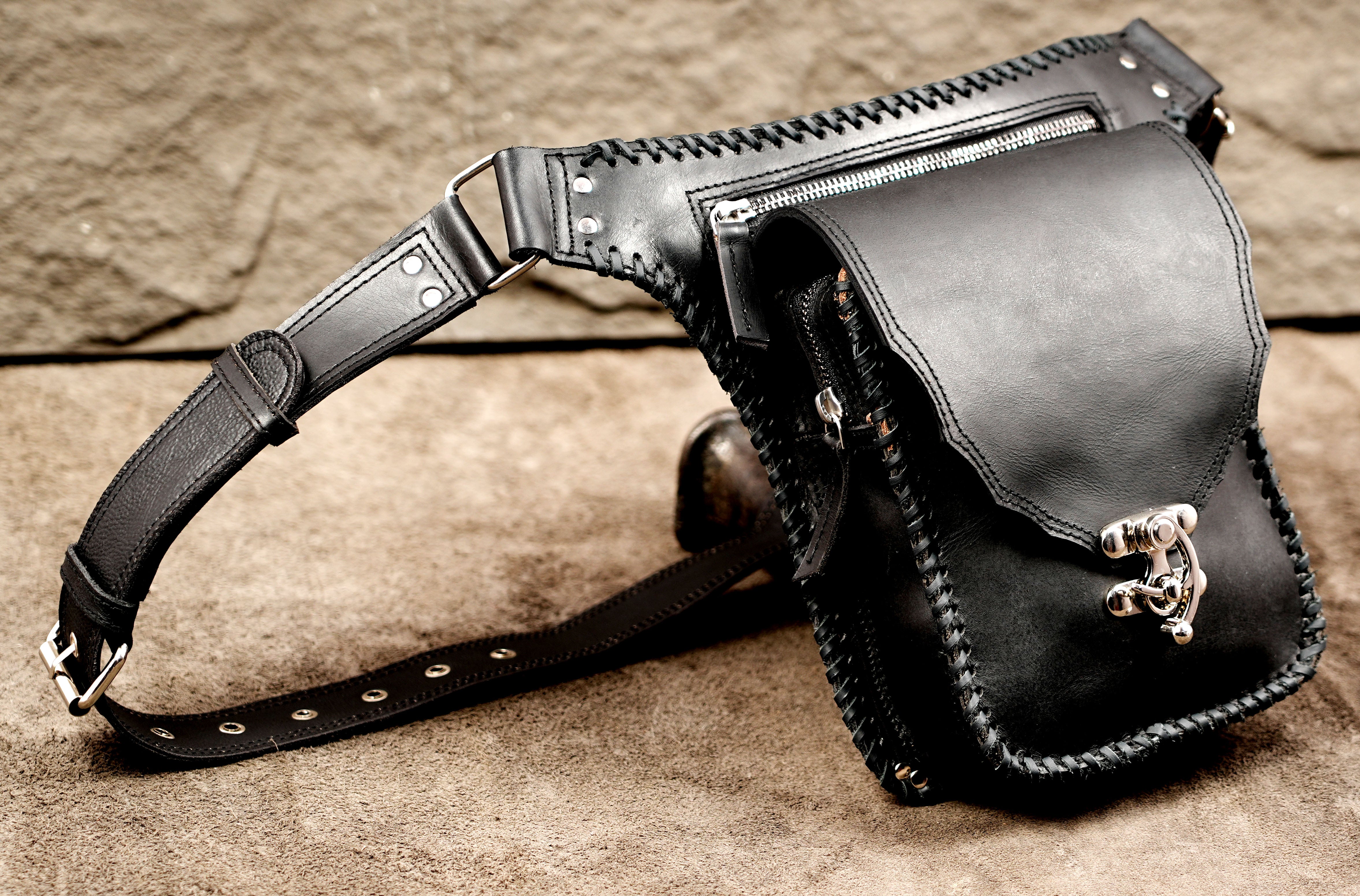 Compact black leather leg bag with heavy-duty silver hardware.