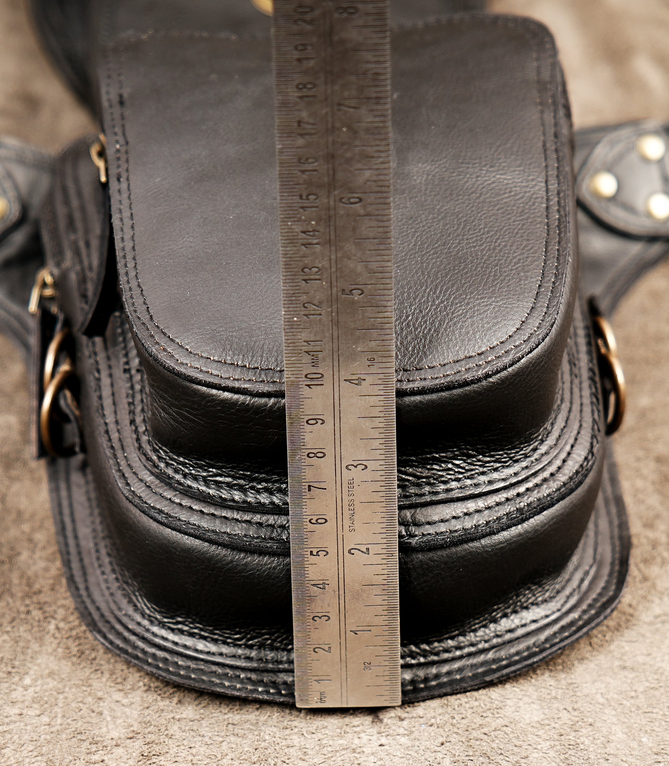 Edgy black leather festival waist pouch featuring heavy brass hardware and braided elements.