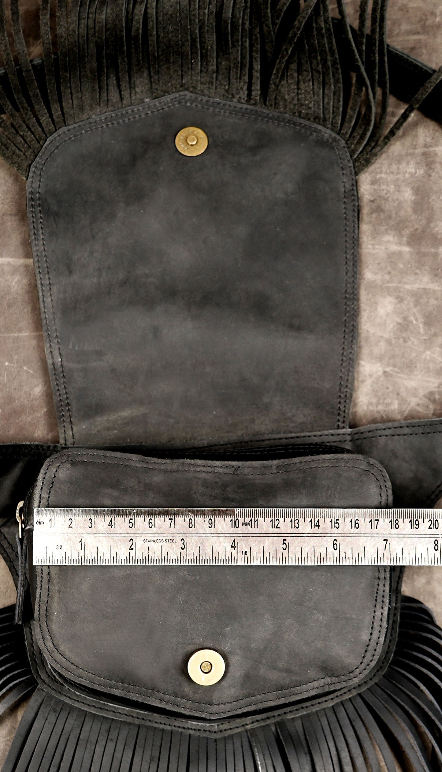 Black leather fringe waist bag with adjustable strap for festivals and travel.