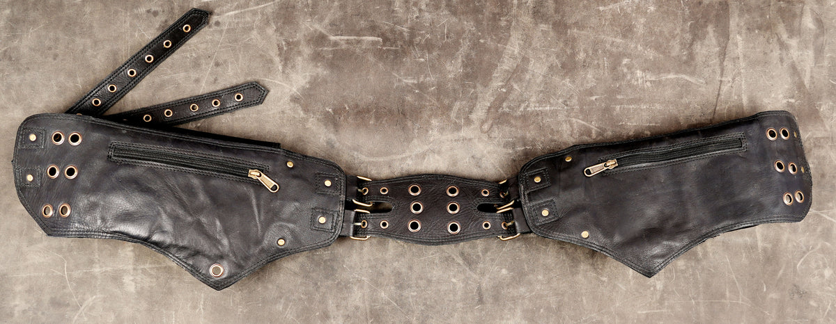 Three-pocket black leather hip pack with antique brass-tone ring accents.
