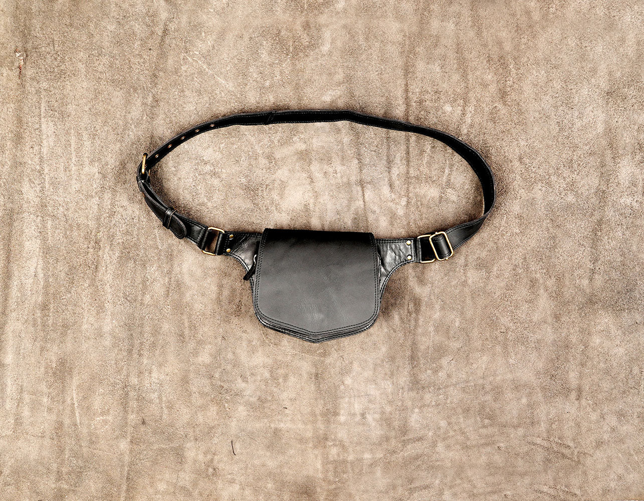 Black leather fanny pack with adjustable waist strap and brass hardware.