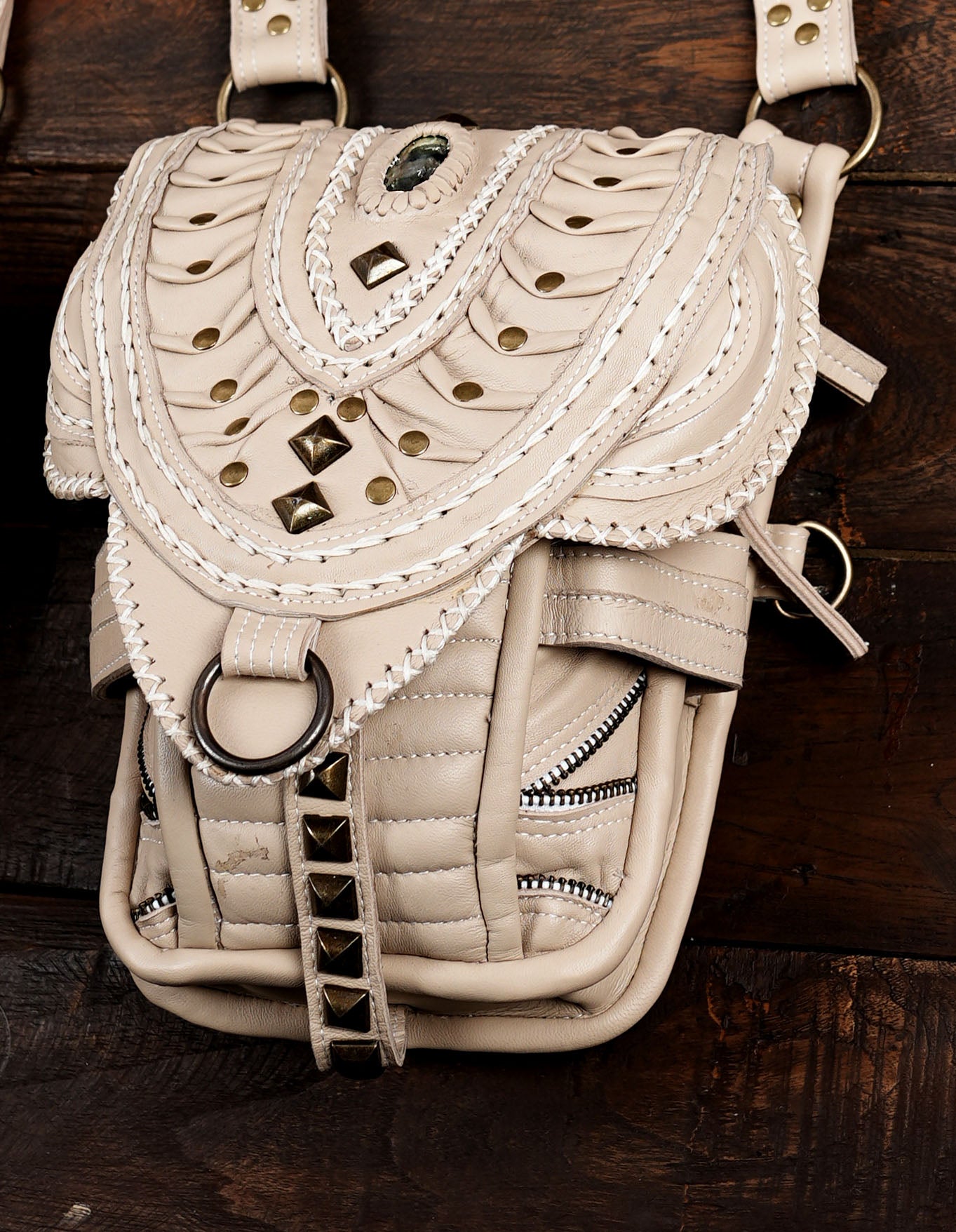 Cream leather shoulder holster bag with detailed woven pocket flaps.