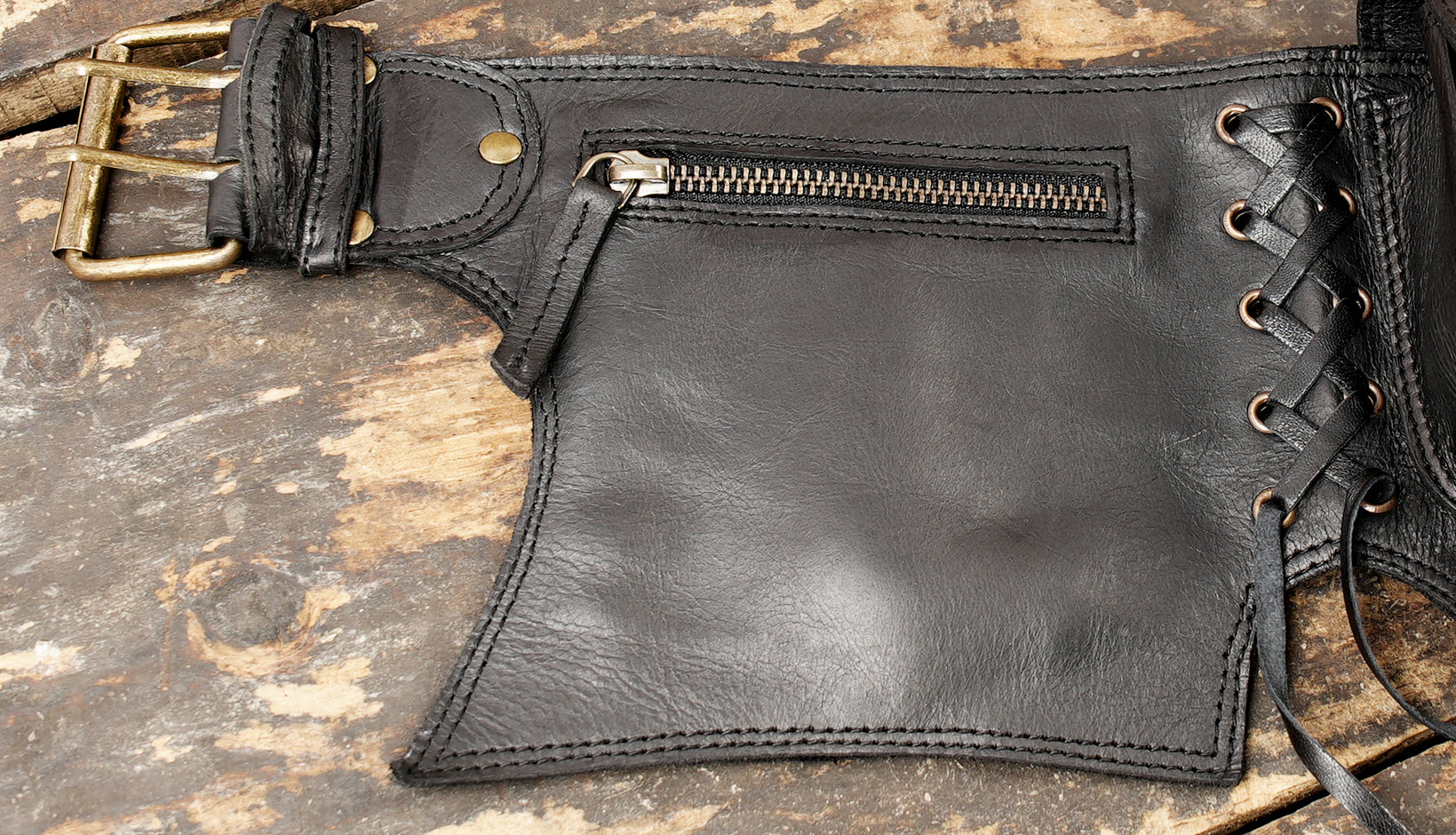 Heavy-duty black leather hip bag belt with zipper compartment, snap pouches, and dangling leather ties.