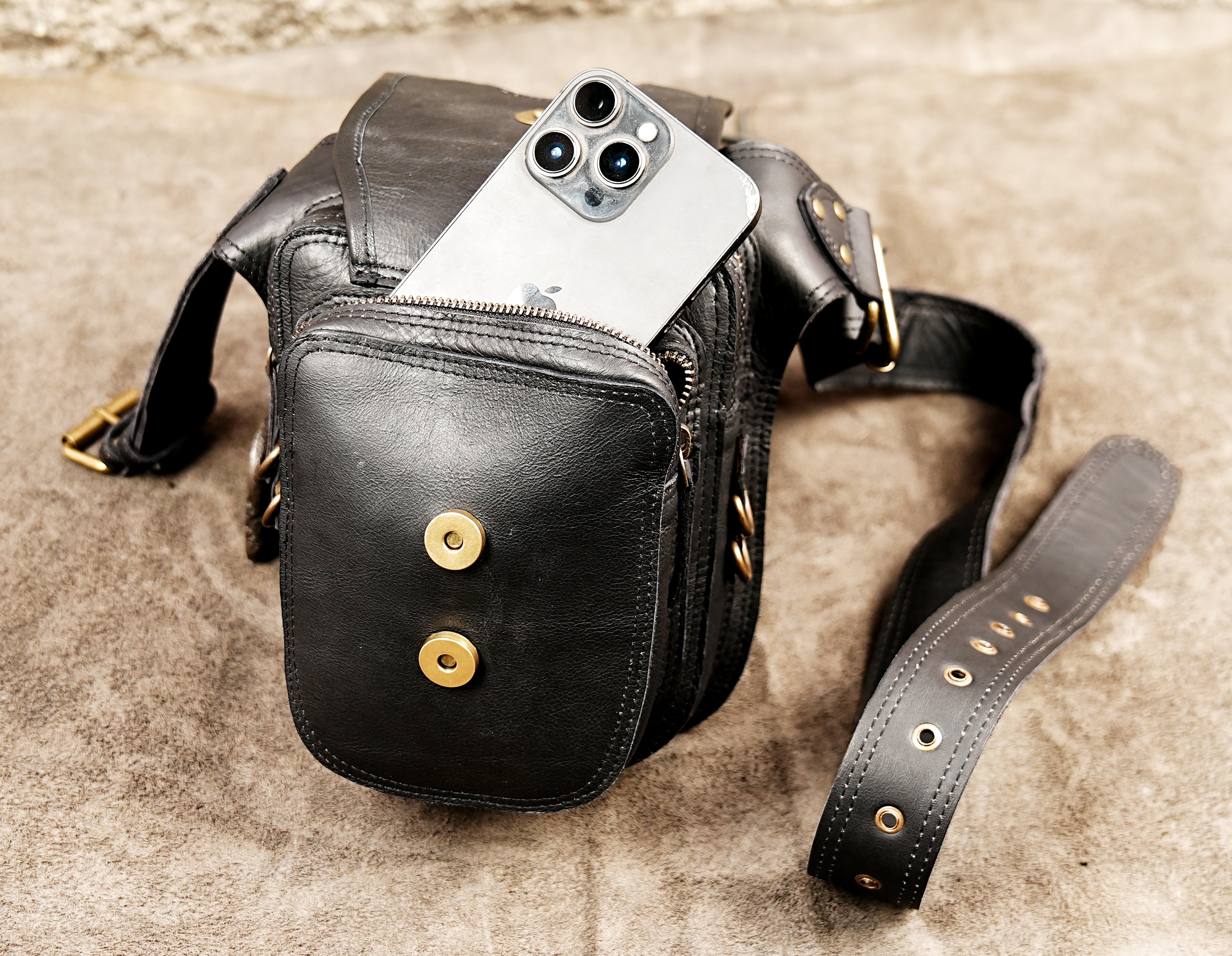 Black leather travel waist bag with secure compartments and decorative braided trim.