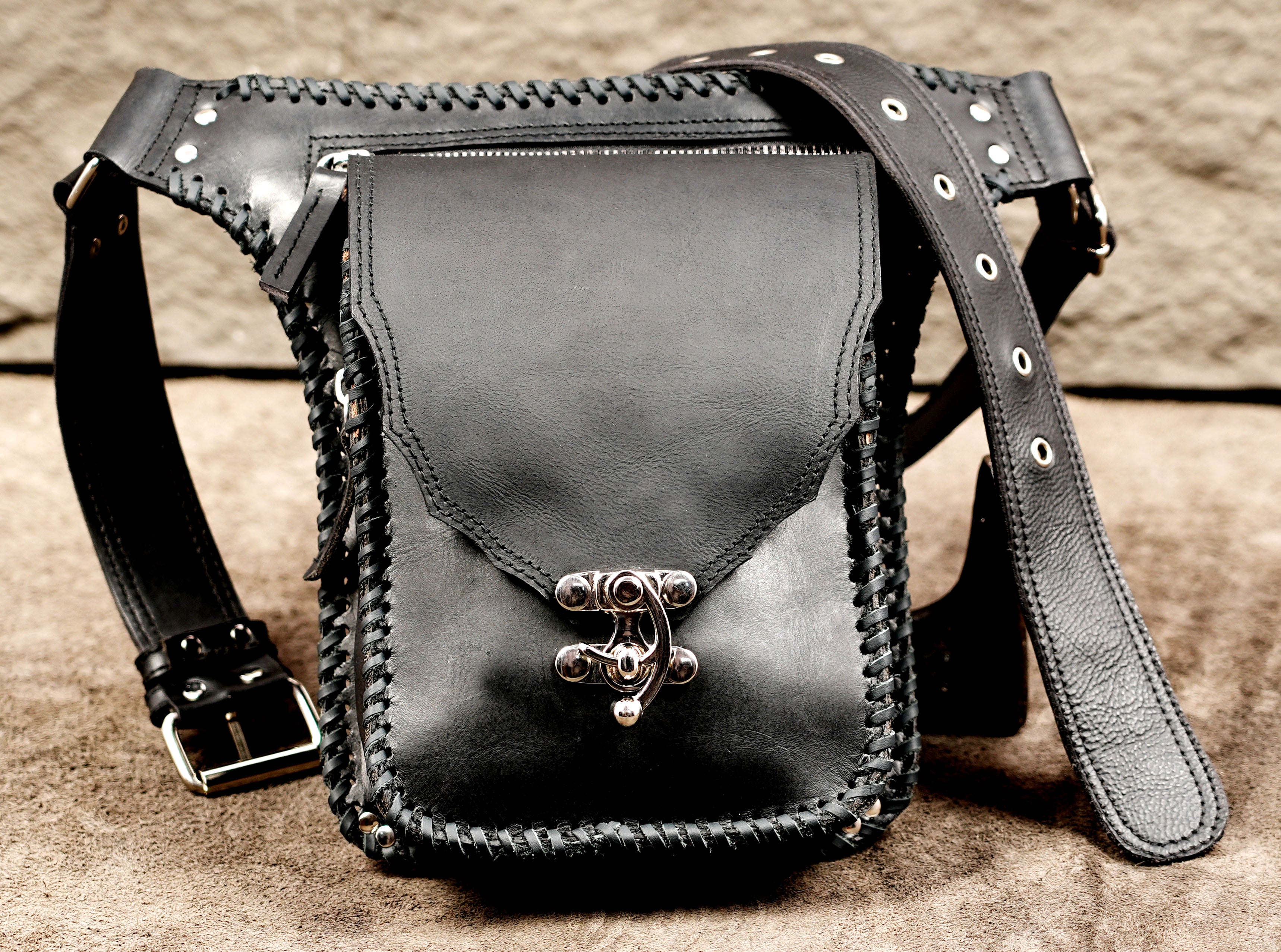 Travel-friendly black leather hip pack with an adjustable buckle strap.