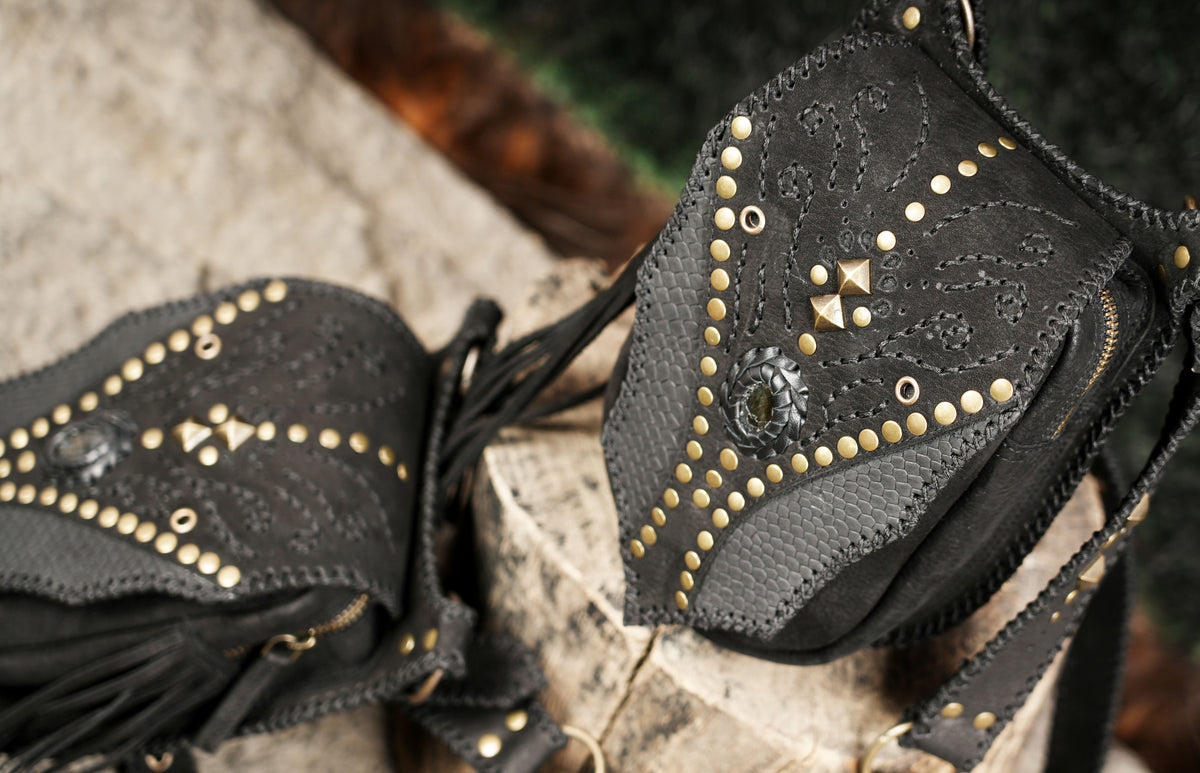 Black leather festival harness with dual pocket holsters and fringe for boho alternative fashion.