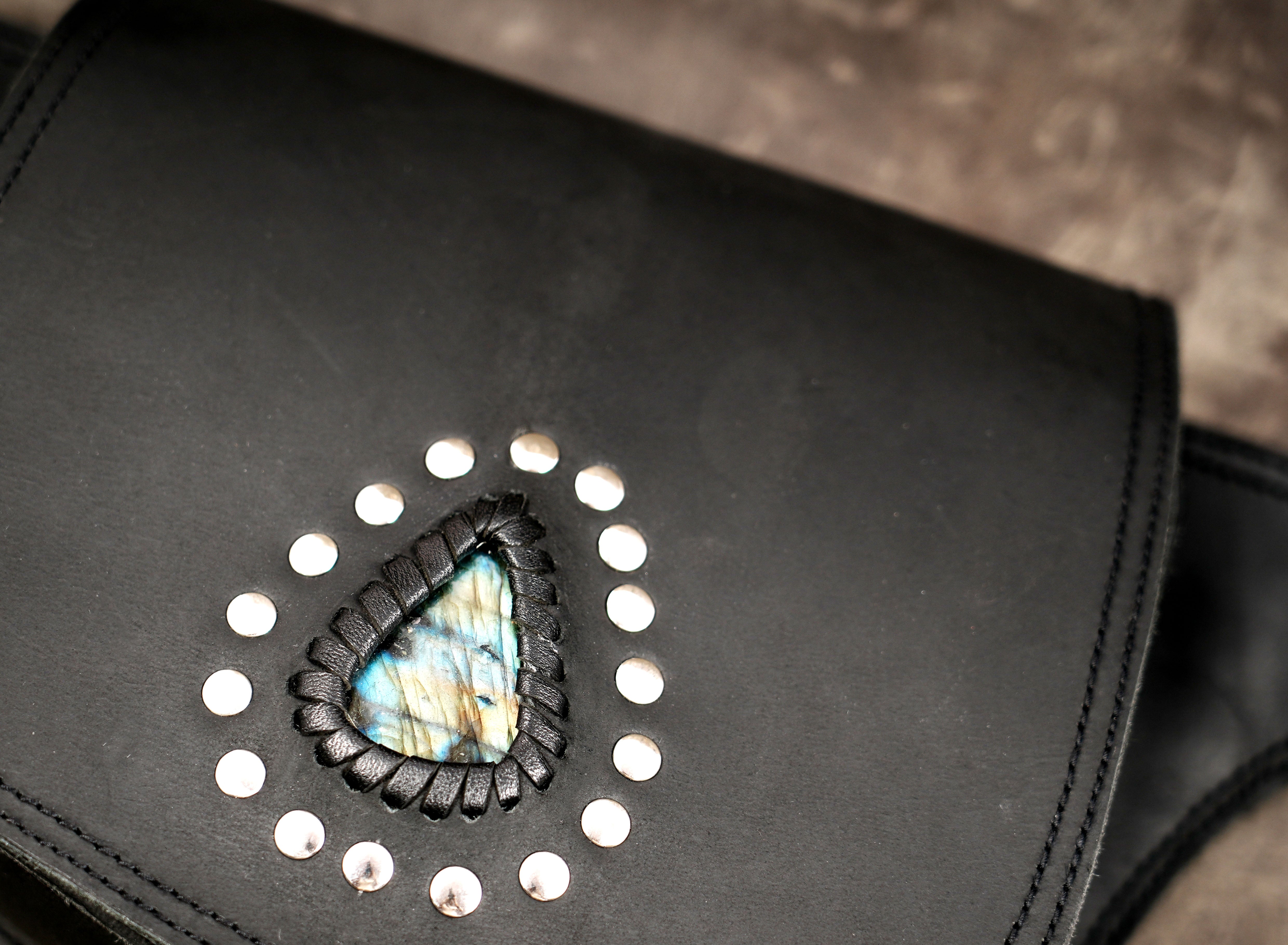 Black leather belt bag with studded teardrop stone, flat lay