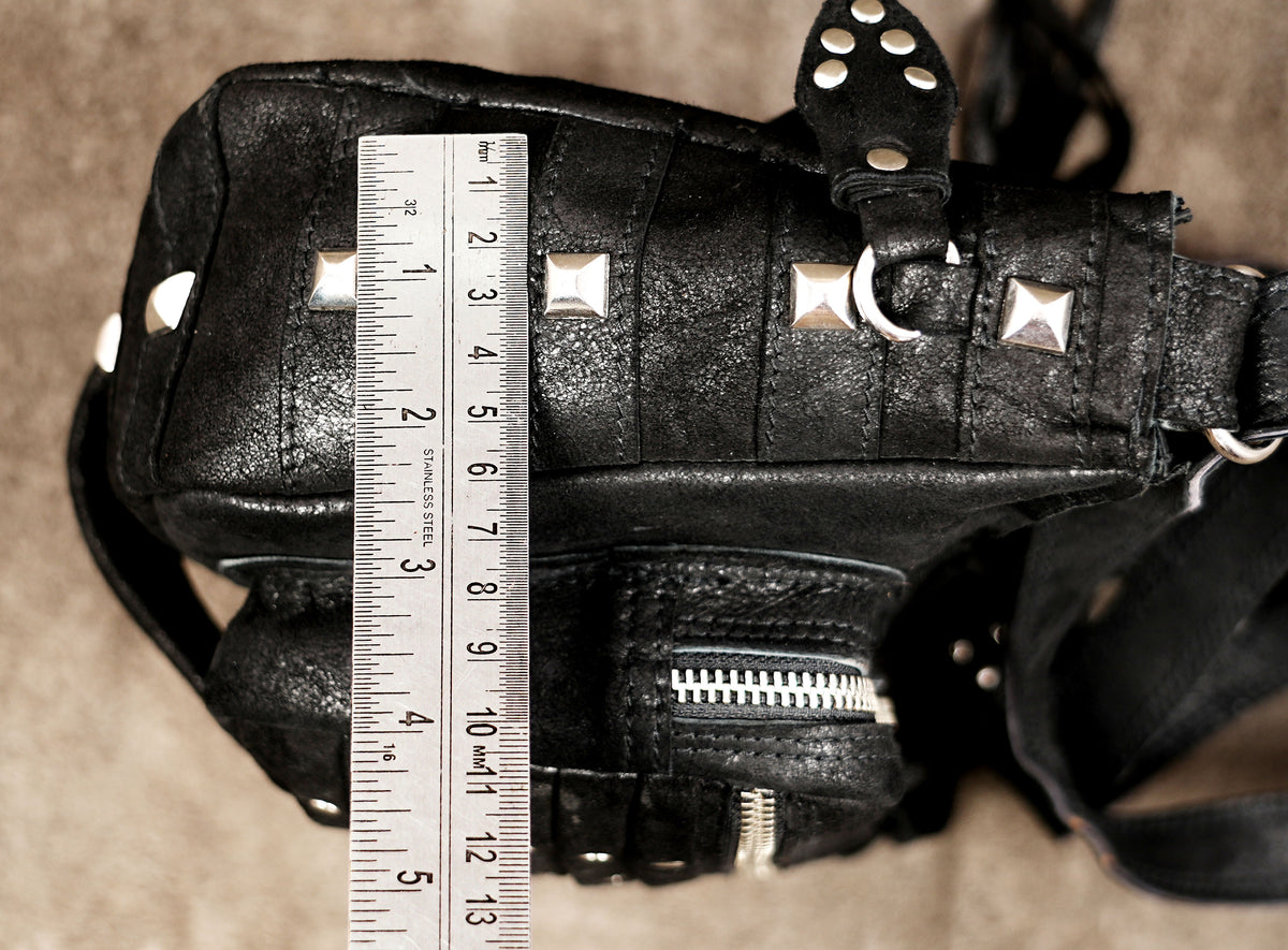 Black leather flap bag with fringe tassels, close up view