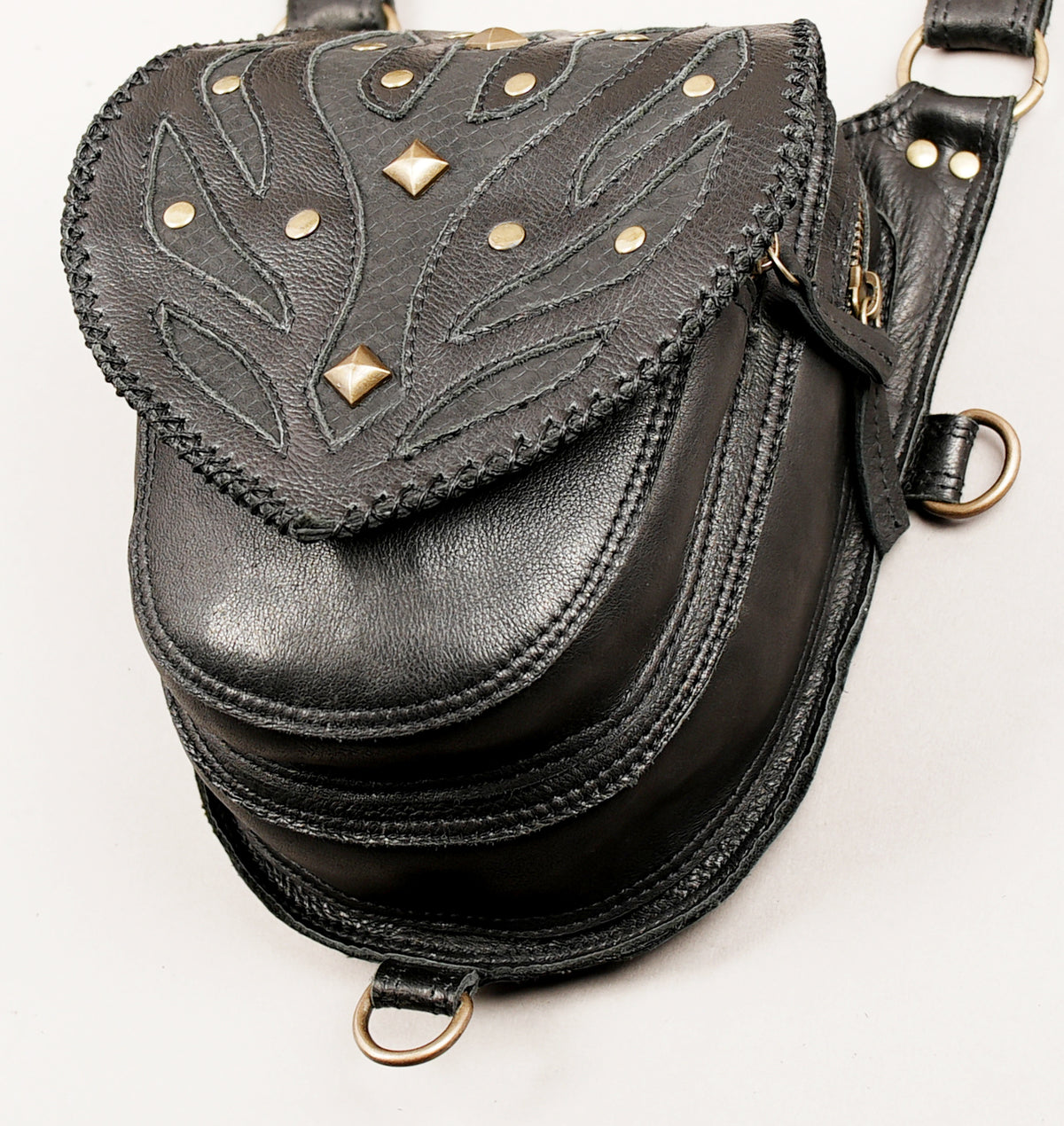 Black leather crossbody bag with a flap cover featuring stitched leaf-like patterns and gold-tone studs and diamond-shaped hardware.