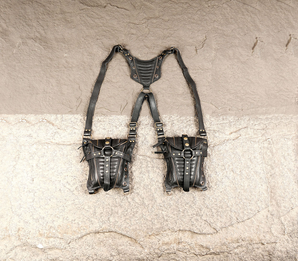 Black leather double holster bag laid flat on a stone background
