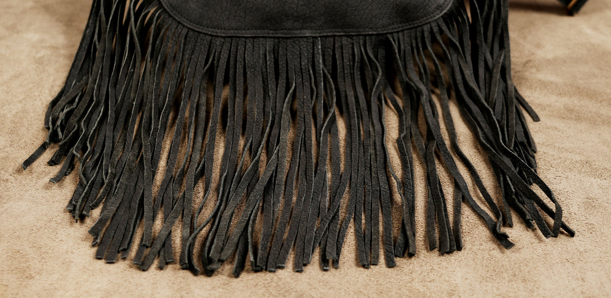 Black festival waist pouch with adjustable belt and flowing fringe for women.