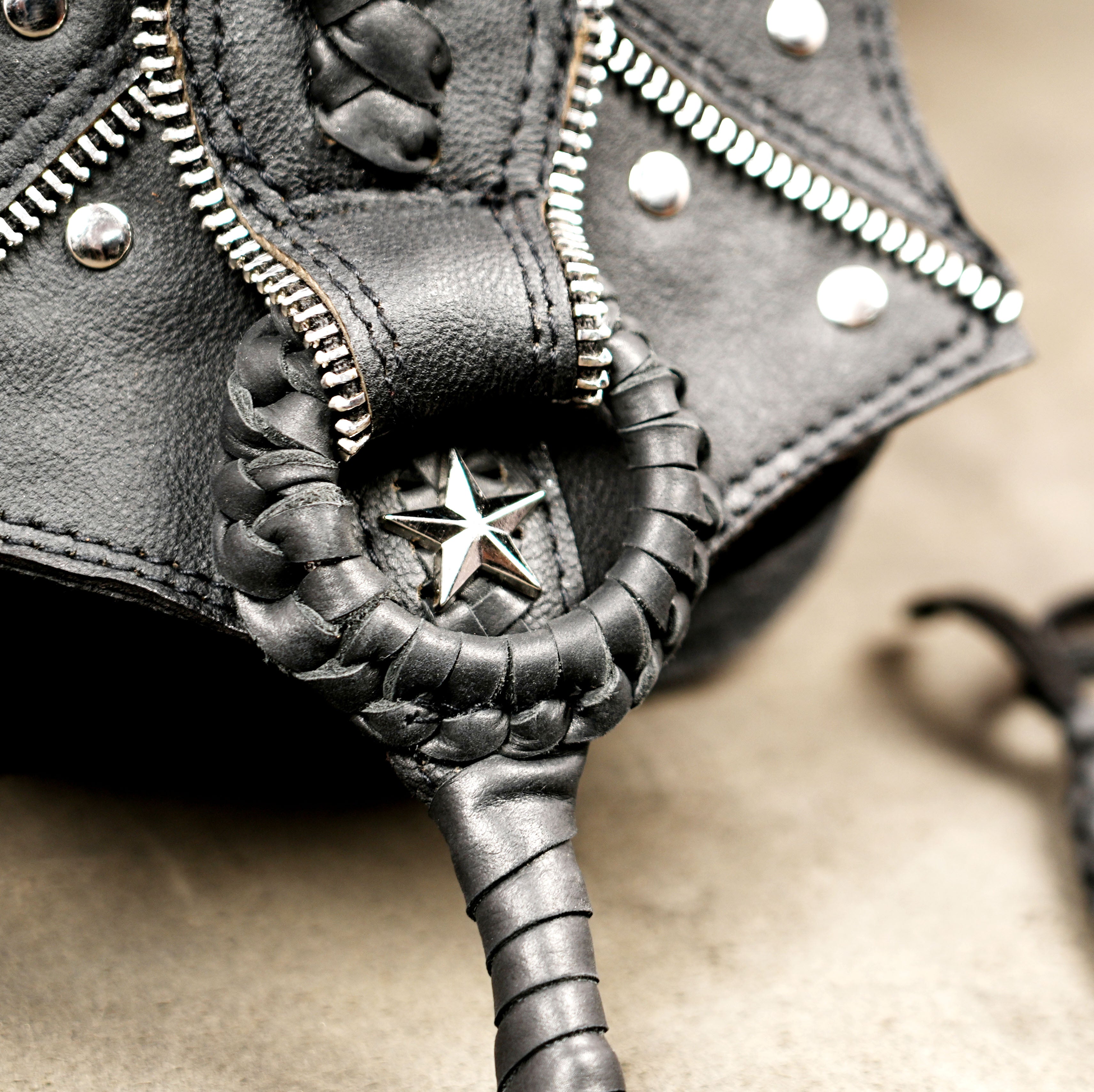 Braided leather belt bag with hanging tassel and silver studs
