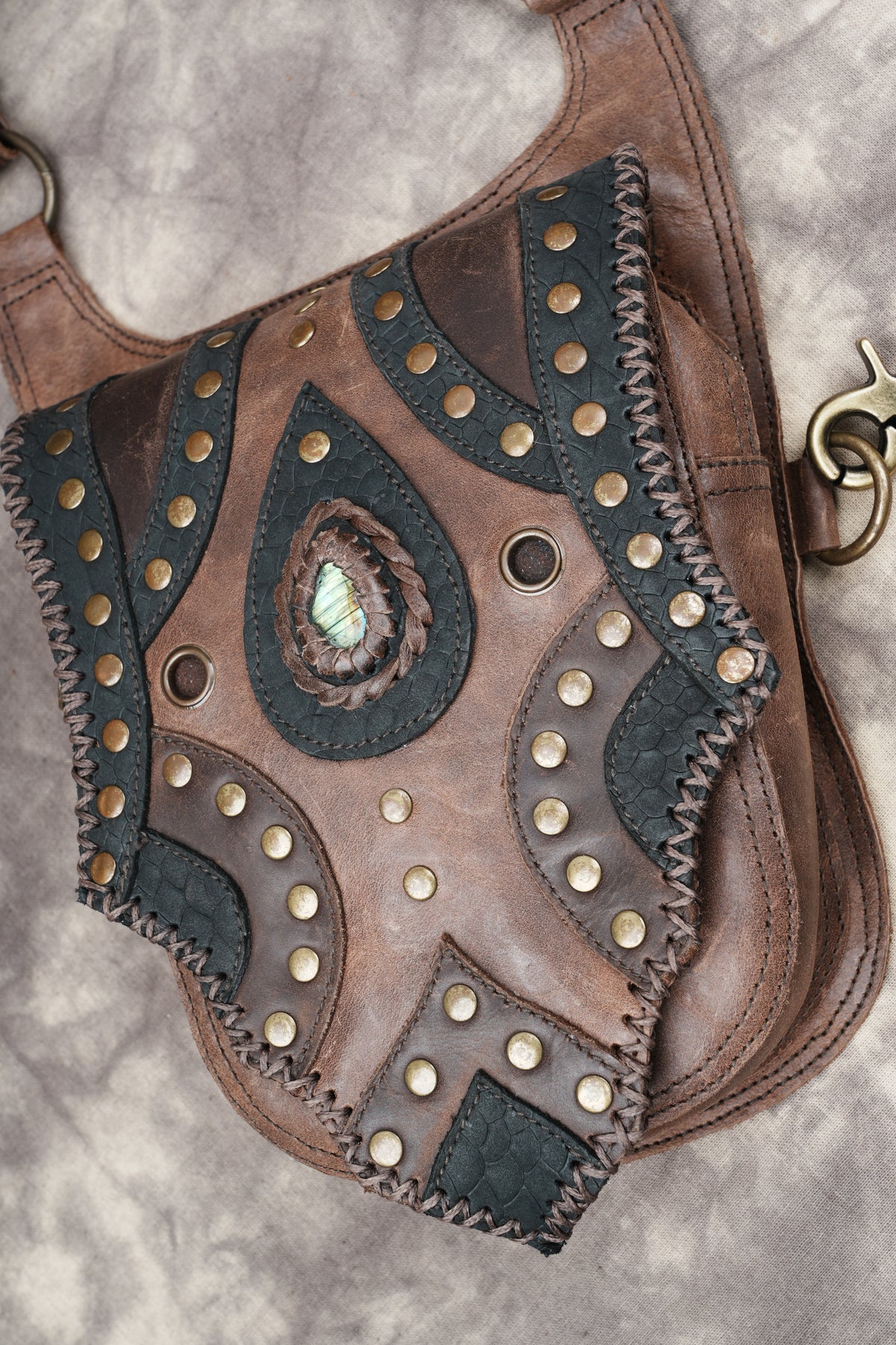 Unisex leather hip bag with adjustable straps and detailed studded flap pockets