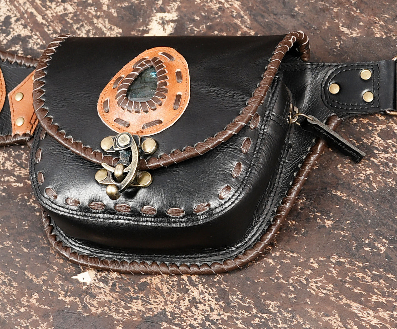 Black leather waist bag with hand-stitched edges and brass hardware