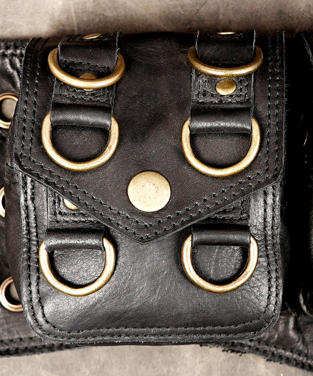 Black utility pocket belt with riveted straps and brass-tone buckle closures.