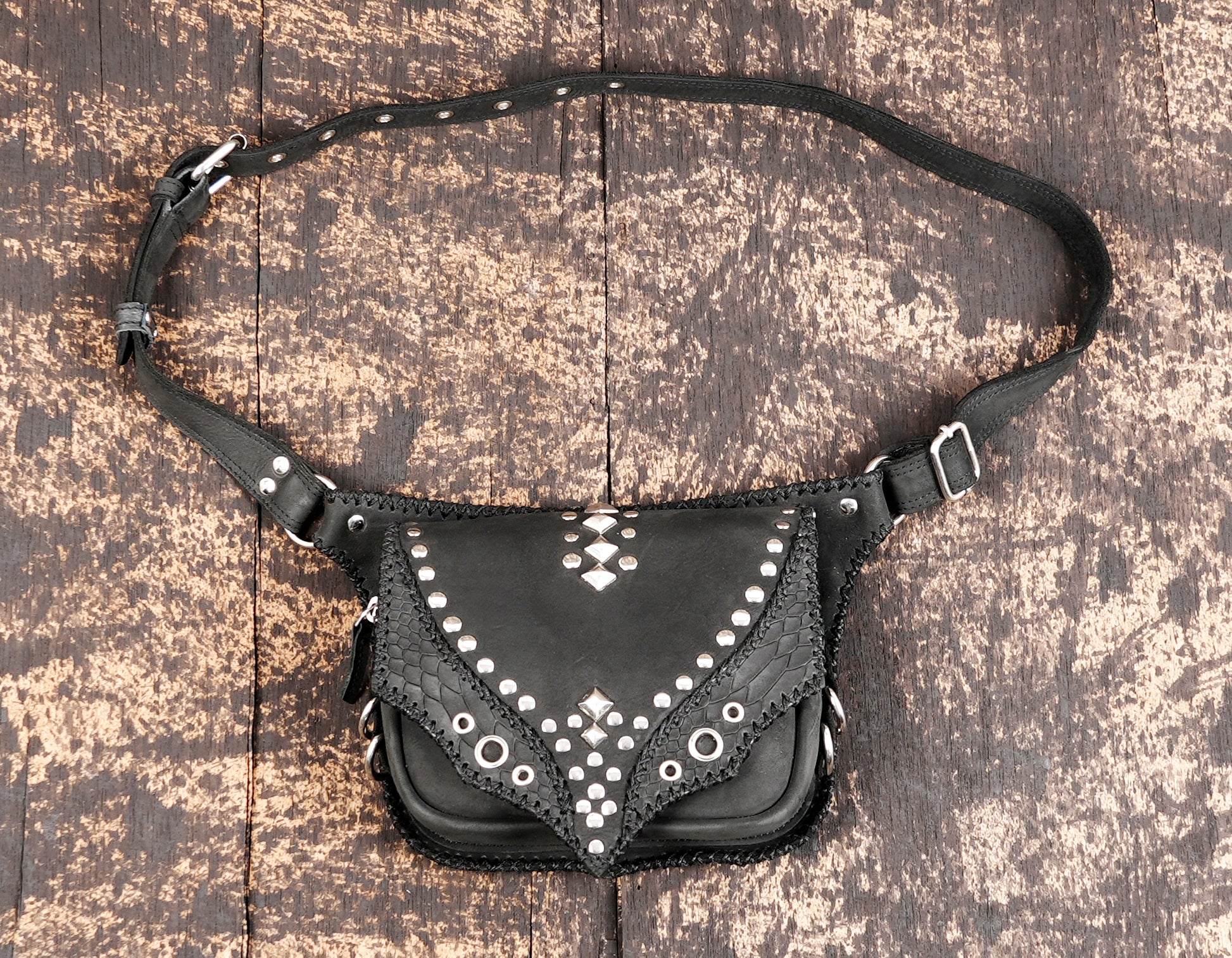 "Black leather waist belt bag with metal studs and textured edges"