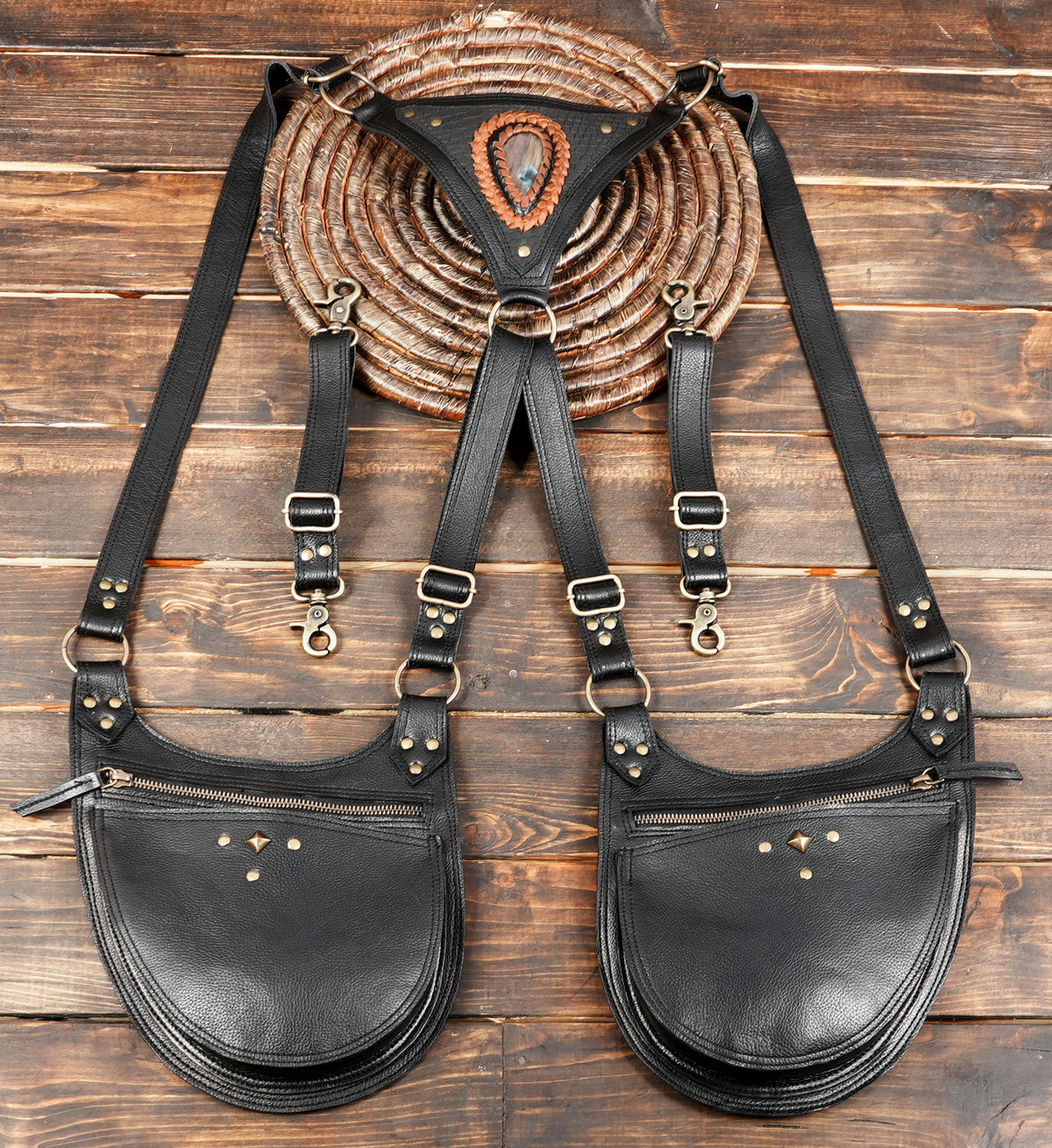 A black leather crossbody bag with dual large front pockets, adjustable shoulder straps, and brass hardware.
