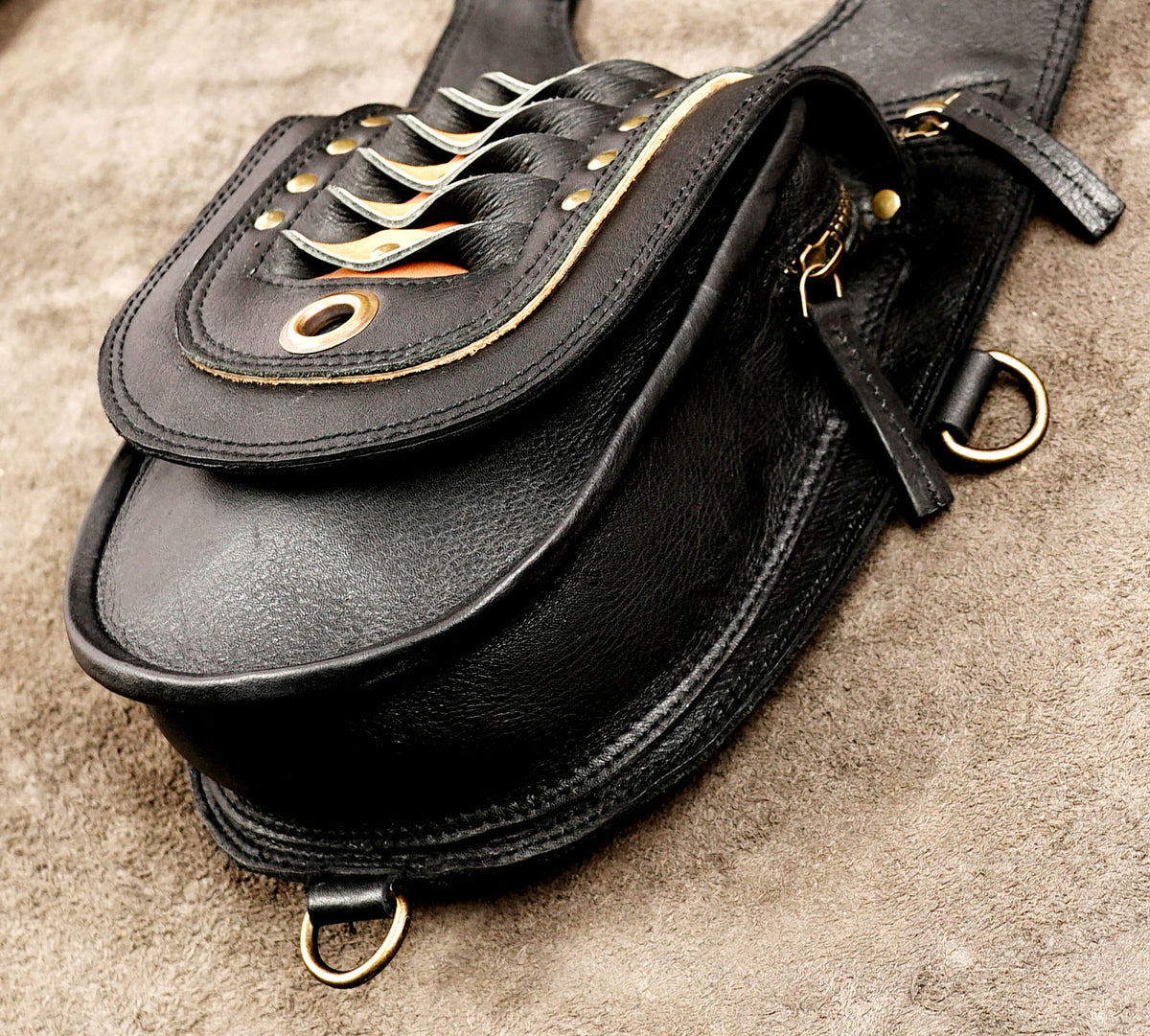 Handmade leather festival bag featuring dual pouches, adjustable harness straps, and orange accents.