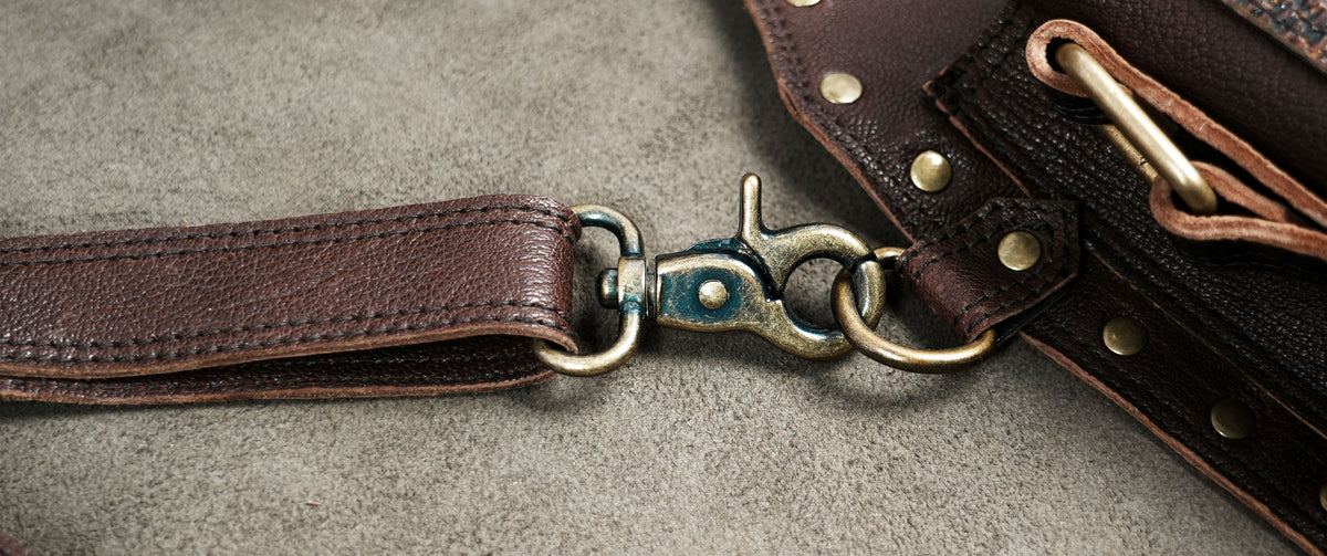 Brown leather body harness bag featuring geometric patterns and decorative metal hardware.