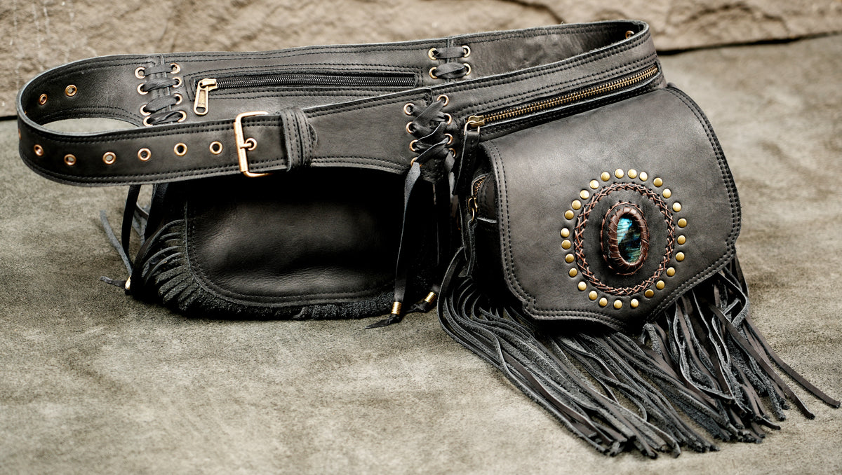 Black leather belt bag set with a large fringed pouch, a zippered side pocket, and a wide adjustable belt strap with brass-tone hardware and lace-up details.