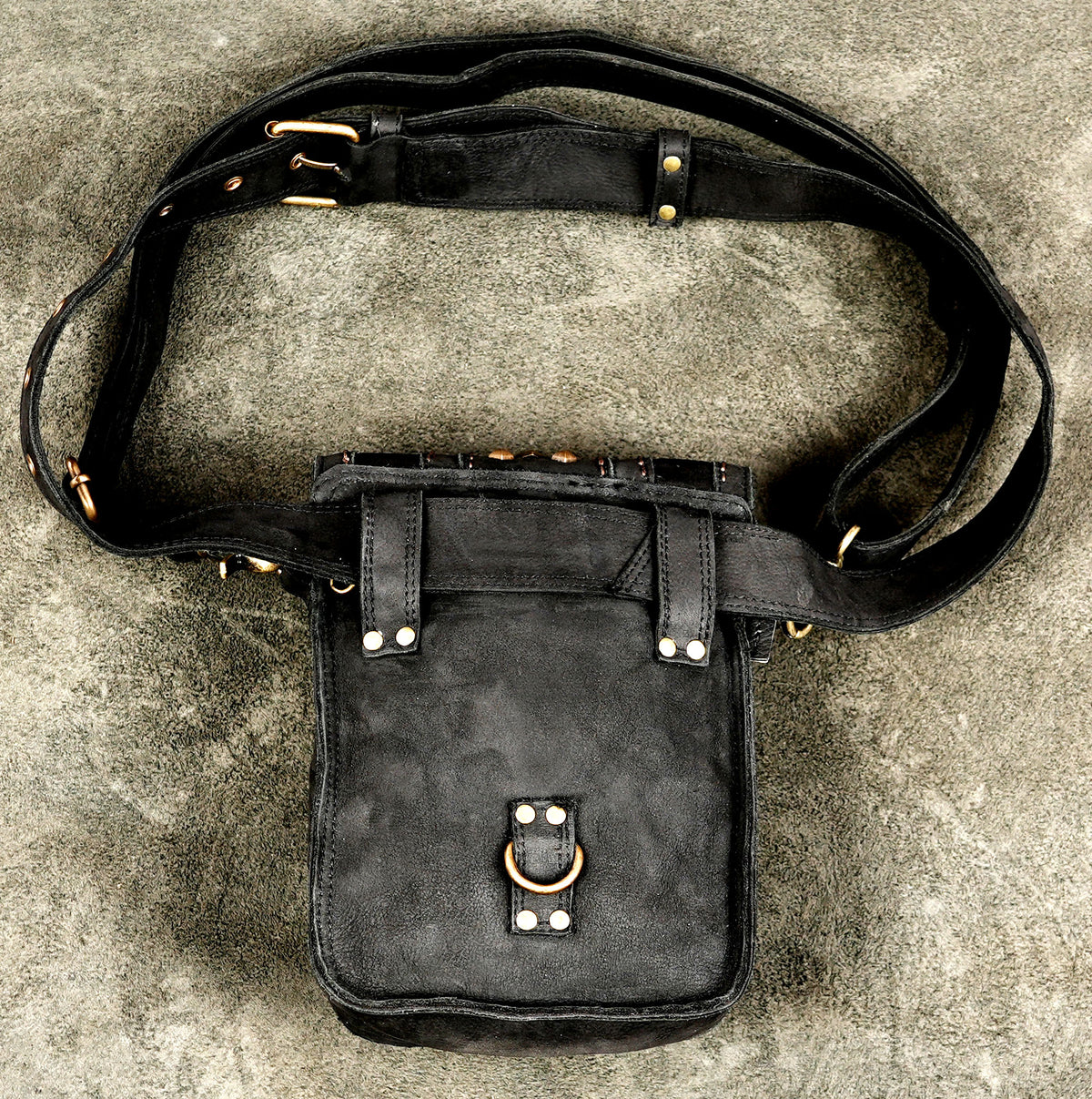 Black leather thigh bag with brass hardware and decorative flap closureBlack leather thigh bag with brass hardware and decorative flap closure