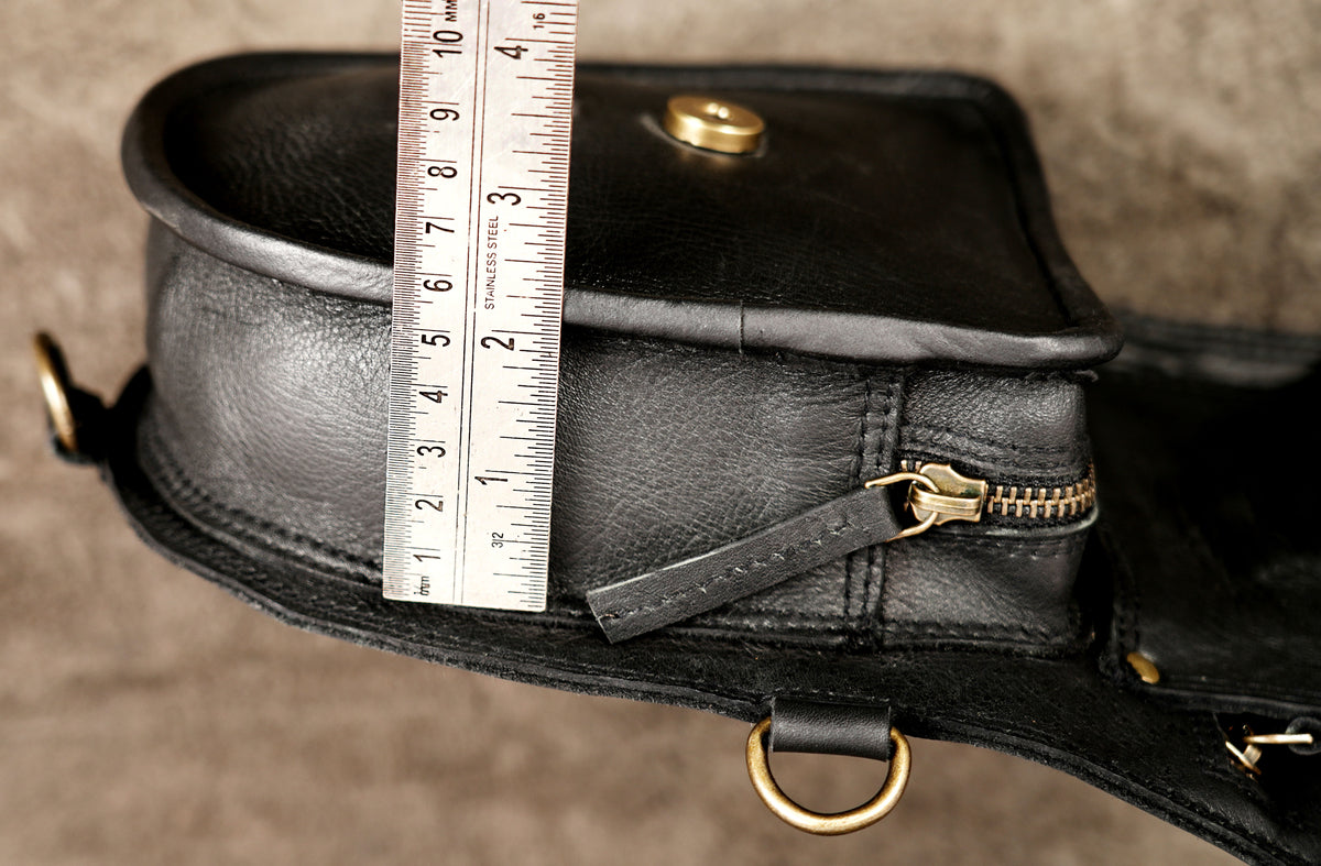 Black leather utility shoulder bag with dual storage pouches and antique brass rings.