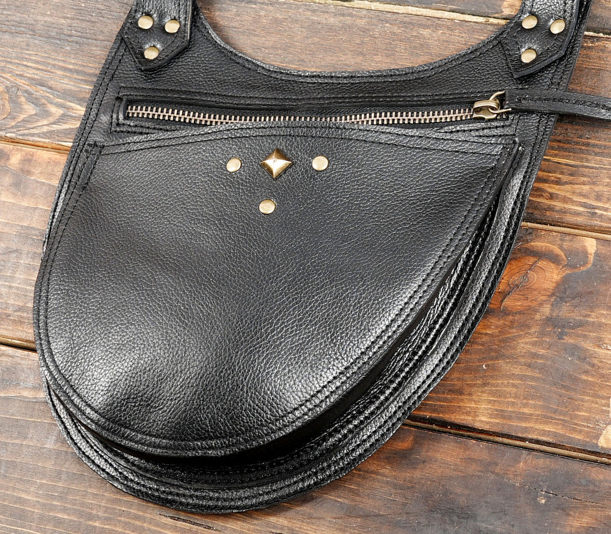 Double pouch black leather harness bag with decorative stitching and metal hardware for festival wear.