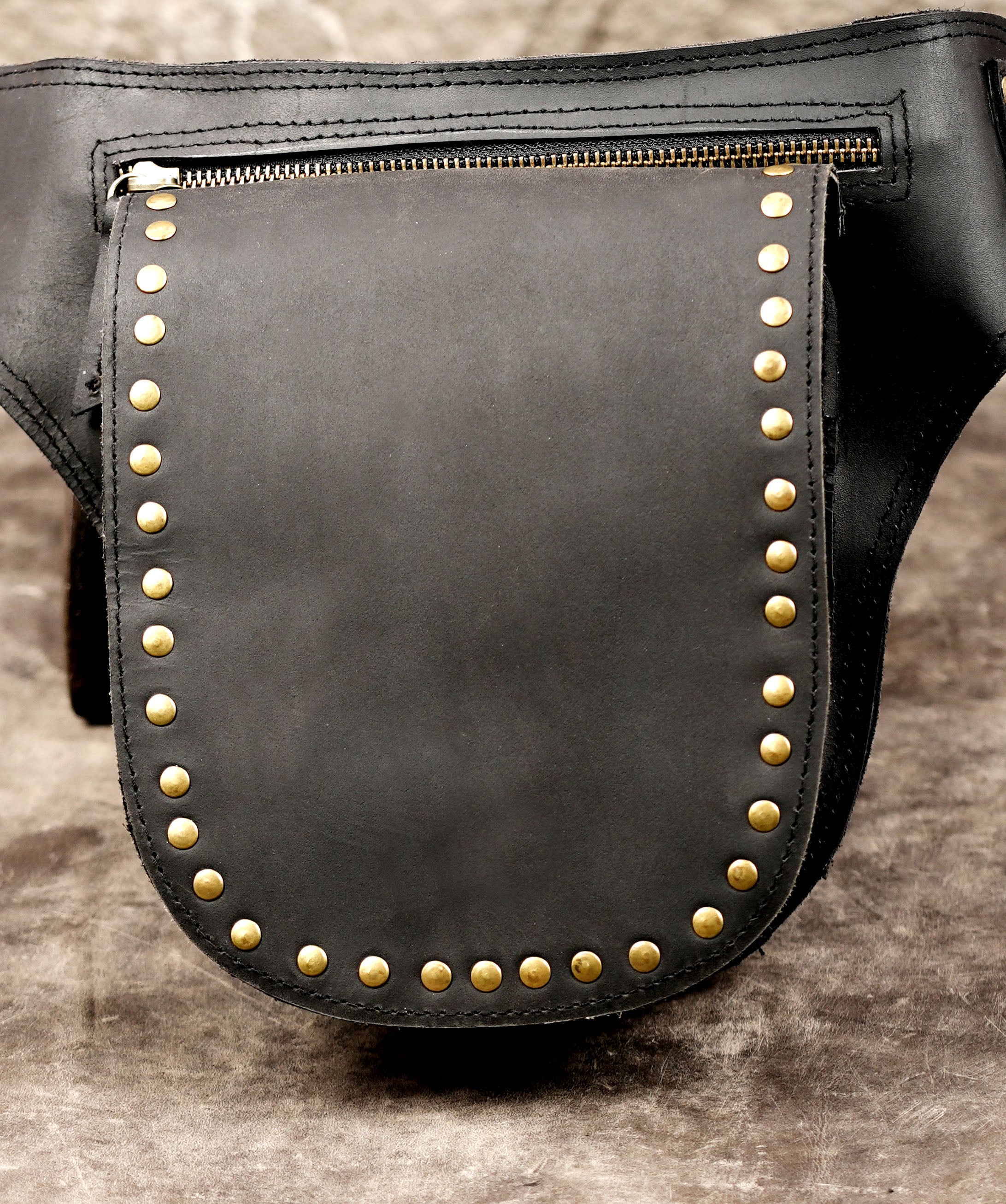Studded leather hip belt with brass ring center, flat lay view