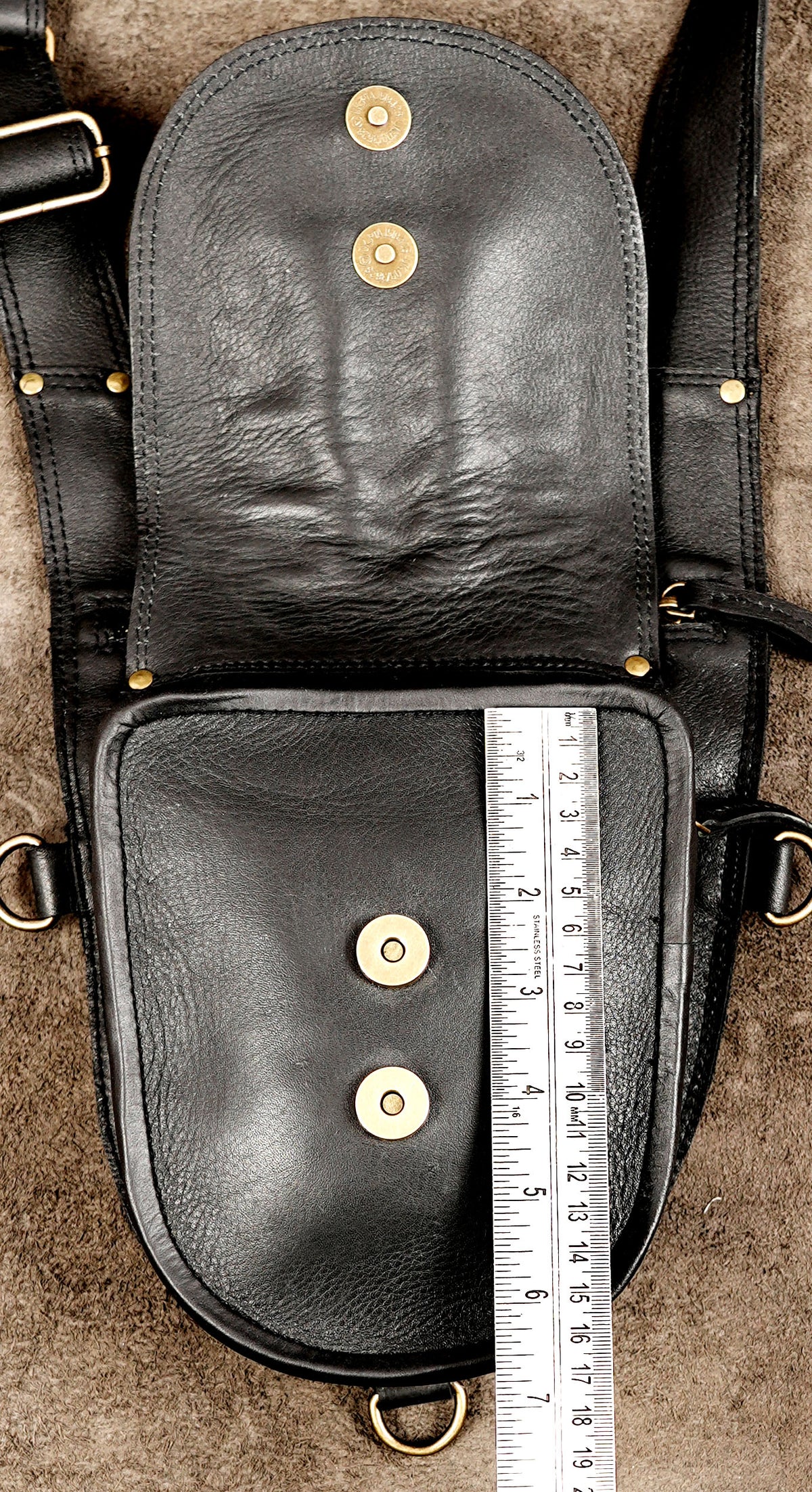Black leather Burning Man harness bag with decorative studs and functional zipper pockets.