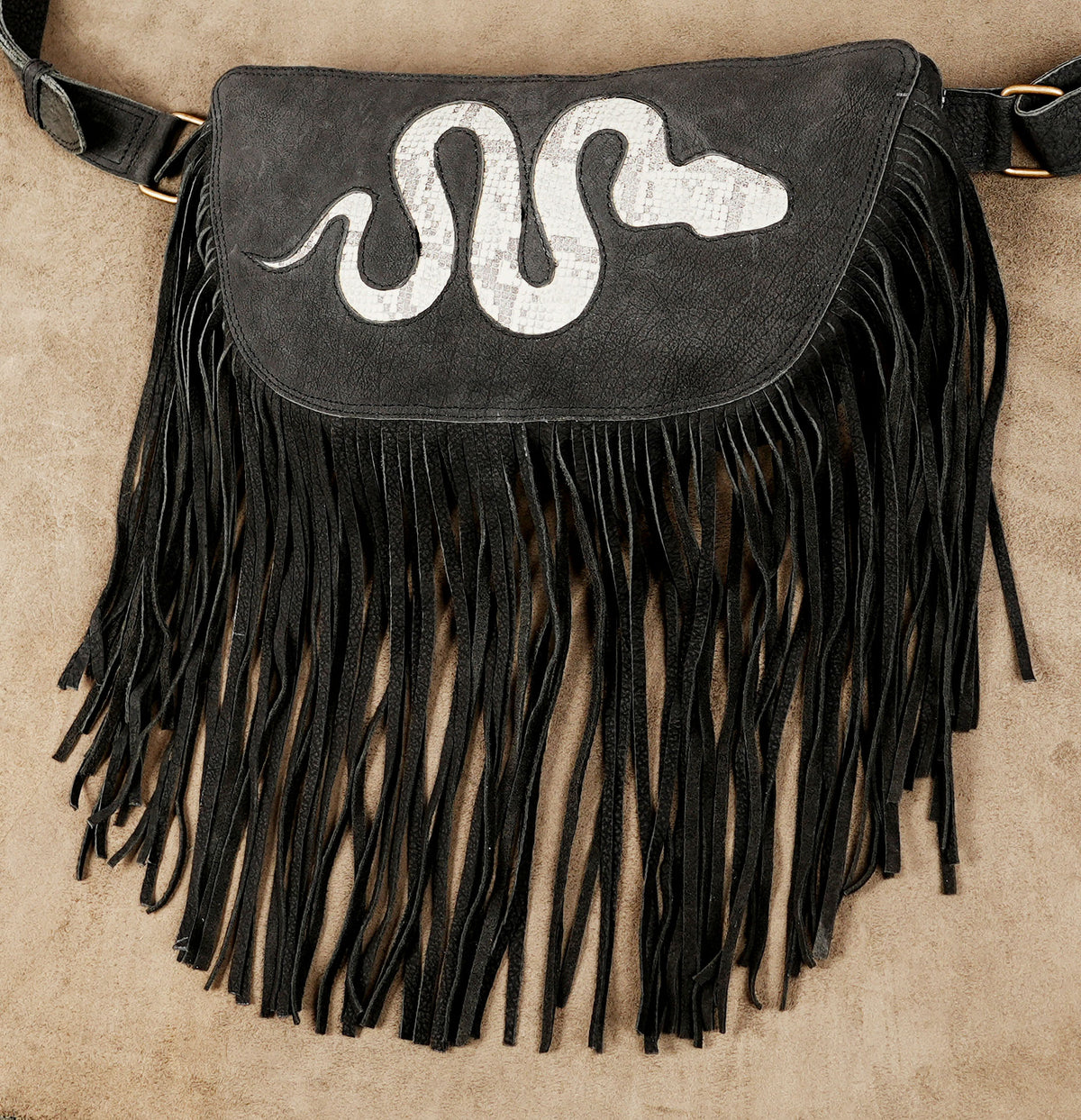 Black statement hip bag with white snake decoration and long fringe for music events.