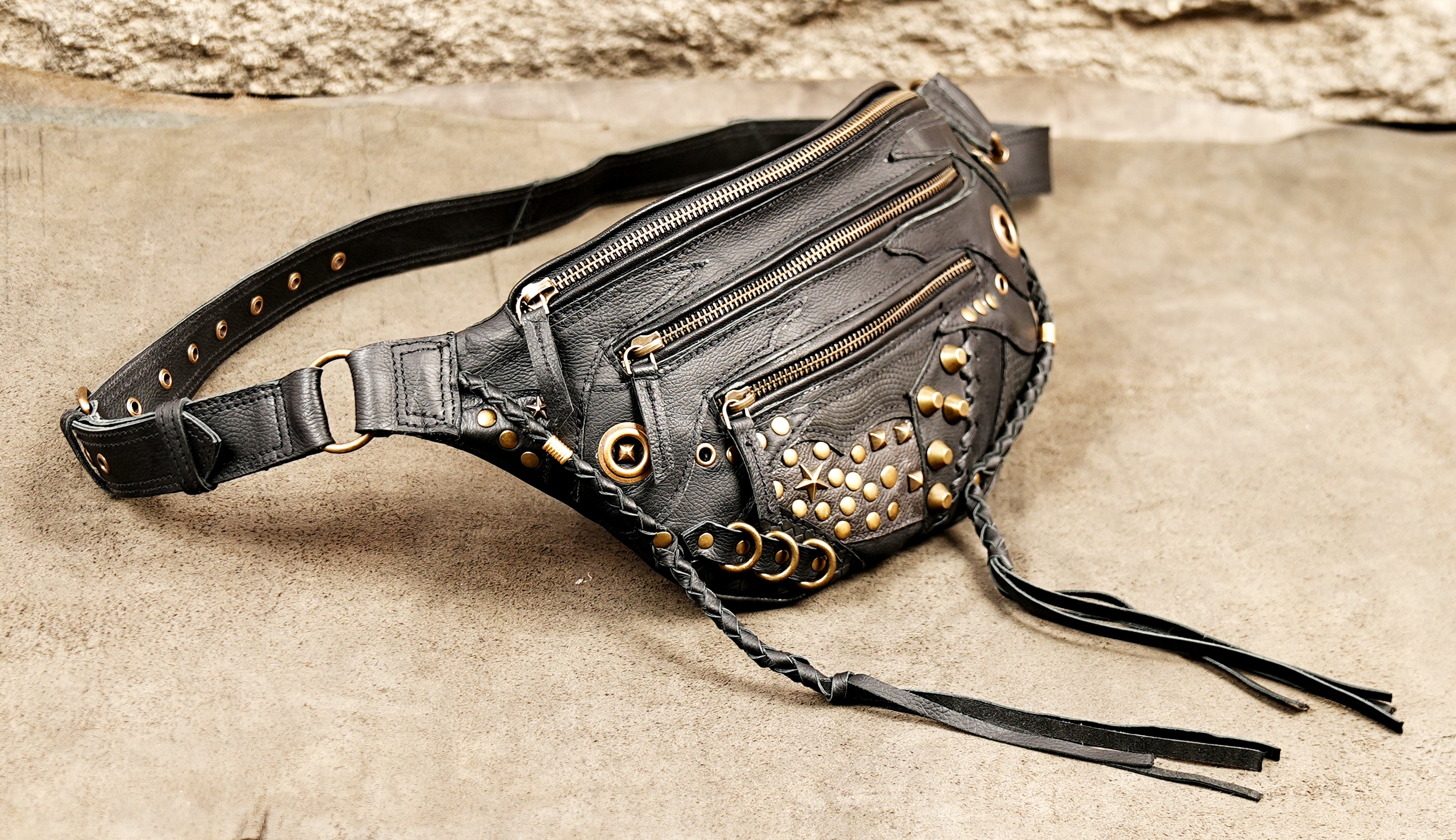Steampunk festival hip bag in black leather with brass grommets, star studs, and long tassels.