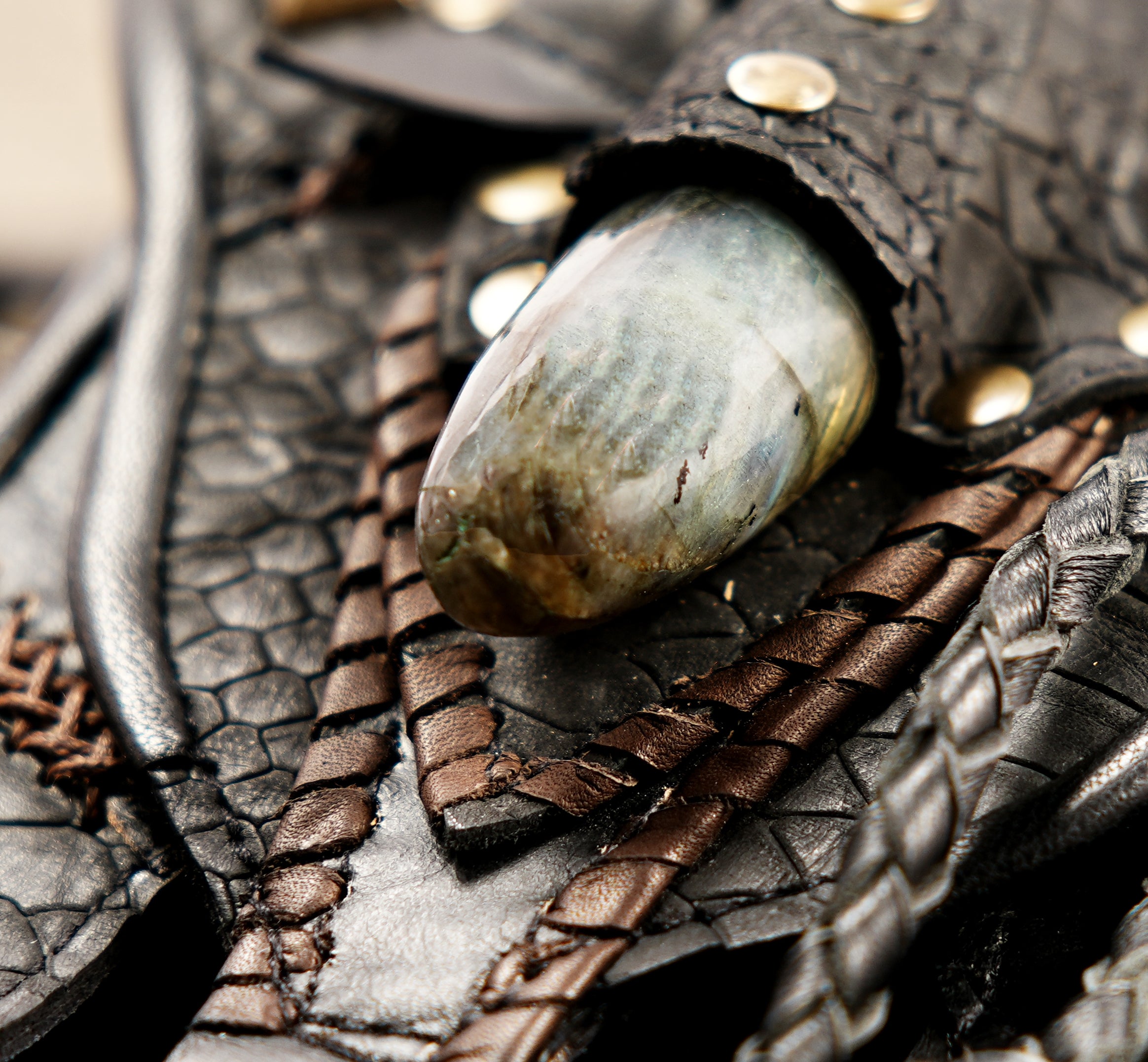 Urban warrior black leather hip pouch with layered textures, brass buckles, and stone detailing.