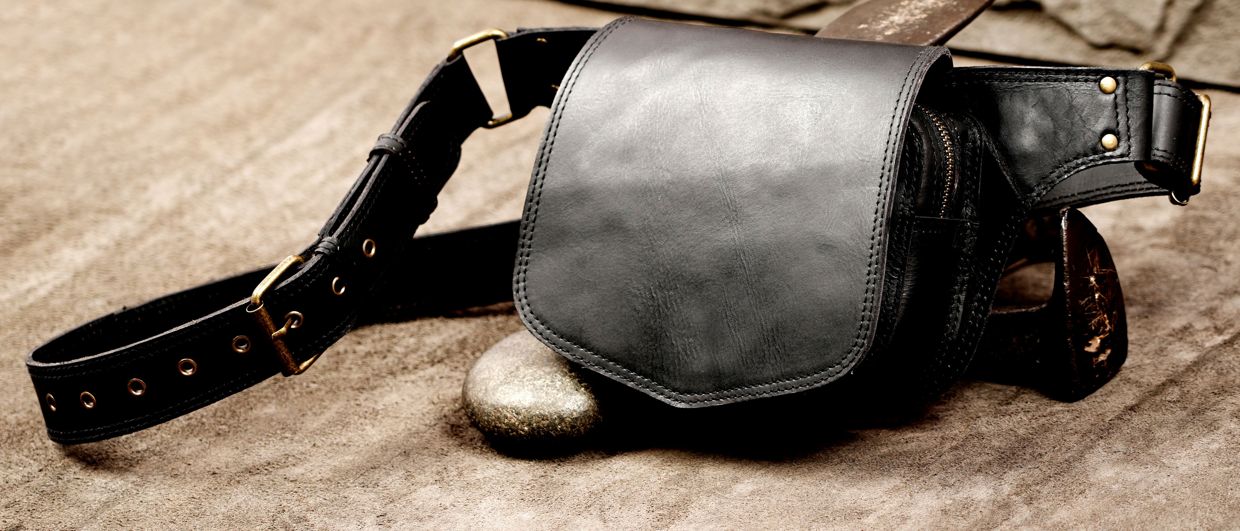 Classic black leather bum bag with an adjustable strap laid flat.