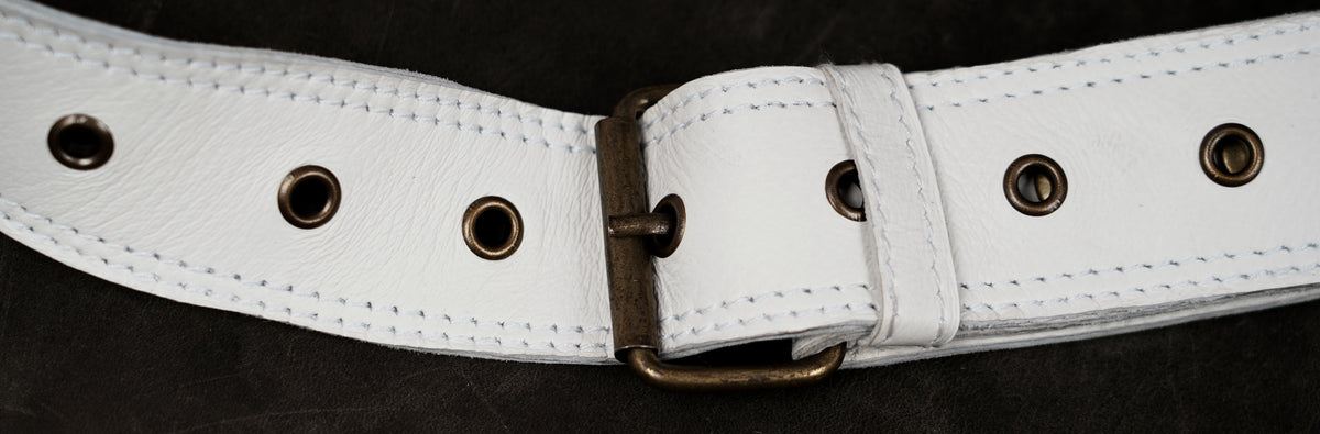 White leather fanny pack with long fringe tassels and metal accents

