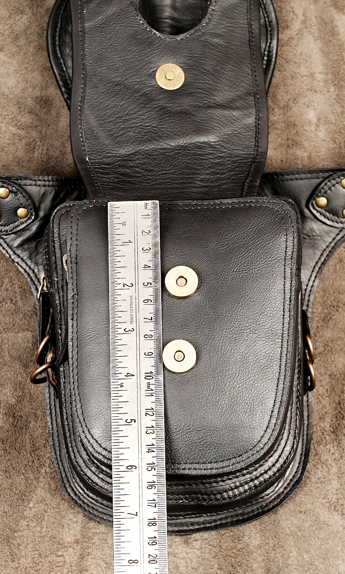 Alternative fashion leather holster bag with braided tassels and a prominent central gemstone.