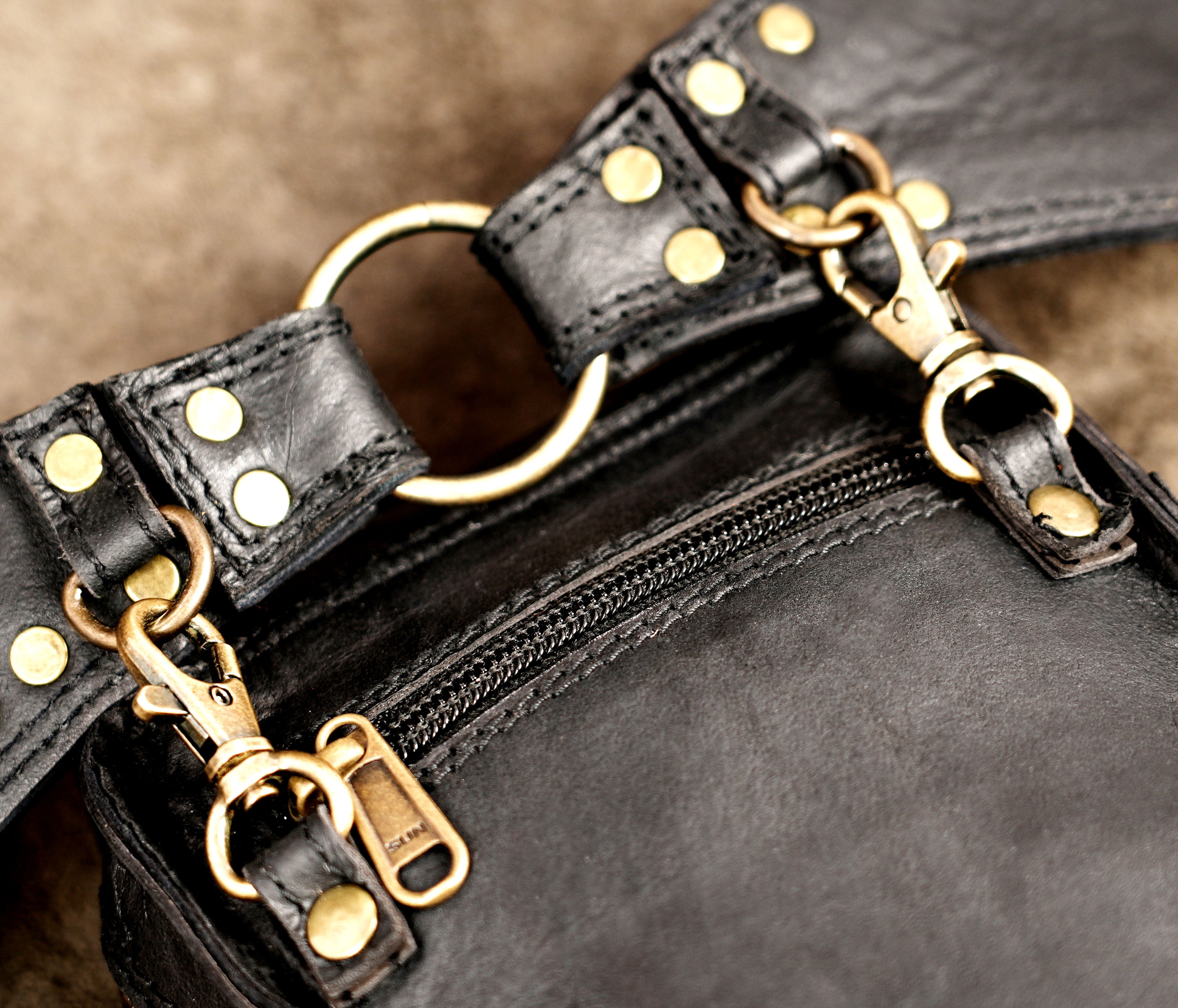 Black leather utility bag with antique brass rings and braided tassel