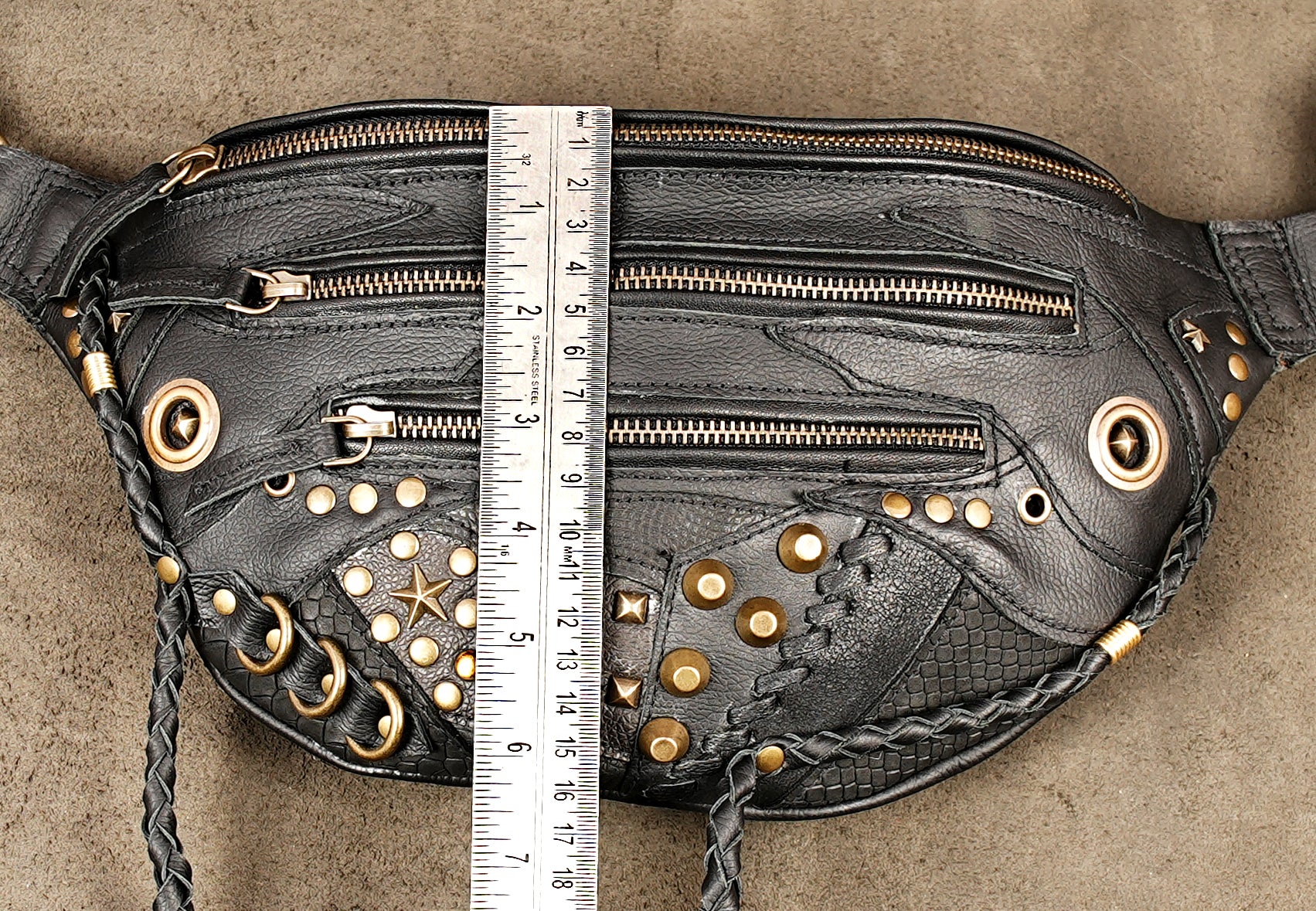 Black leather travel fanny pack with secure zipper pockets and decorative gold rivets.