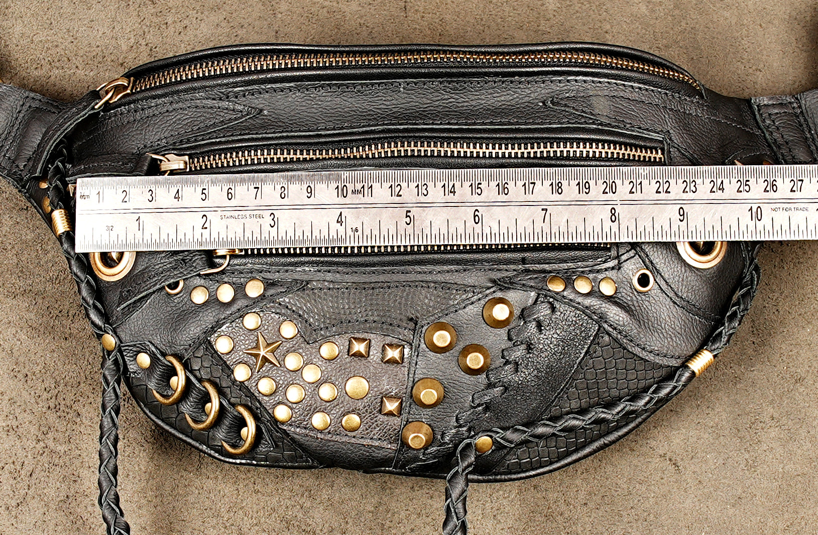Heavy-duty black leather utility waist bag featuring gold star details and hanging braided tassels.