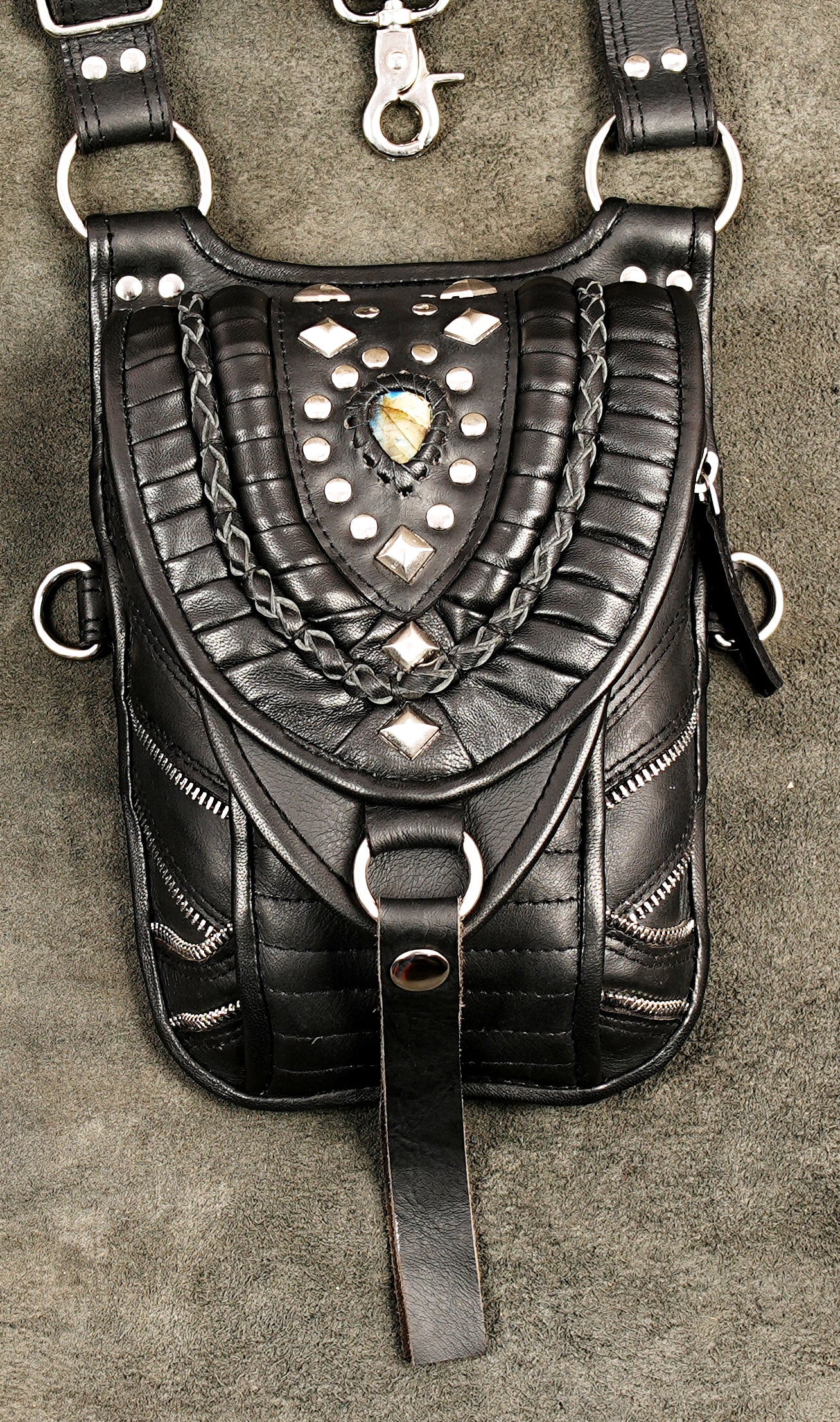 Black genuine leather utility harness bag laid flat on textured background