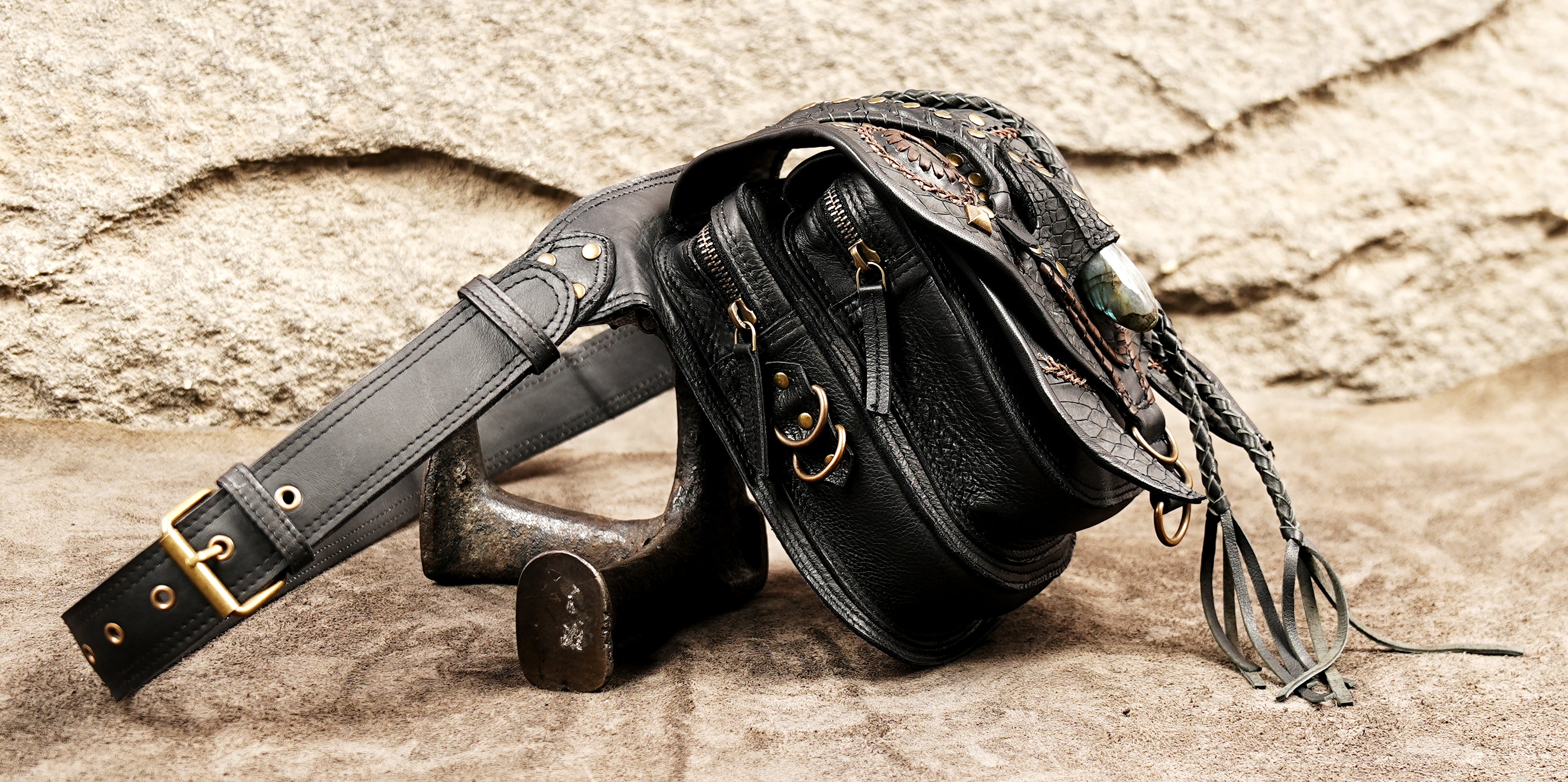 Intricately designed black leather fanny pack with a teardrop stone inlay and brass rivets.