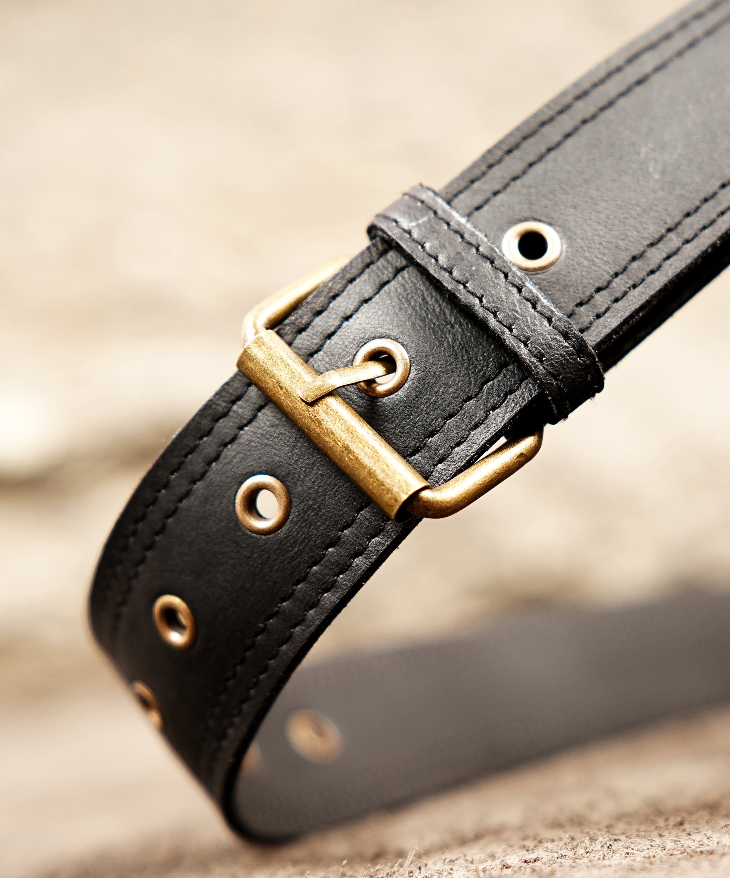 Adjustable black leather holster bag with a wide waist strap and brass metal buckles.