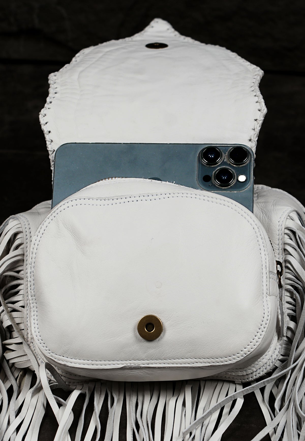White leather crossbody belt bag with decorative fringe and studs

