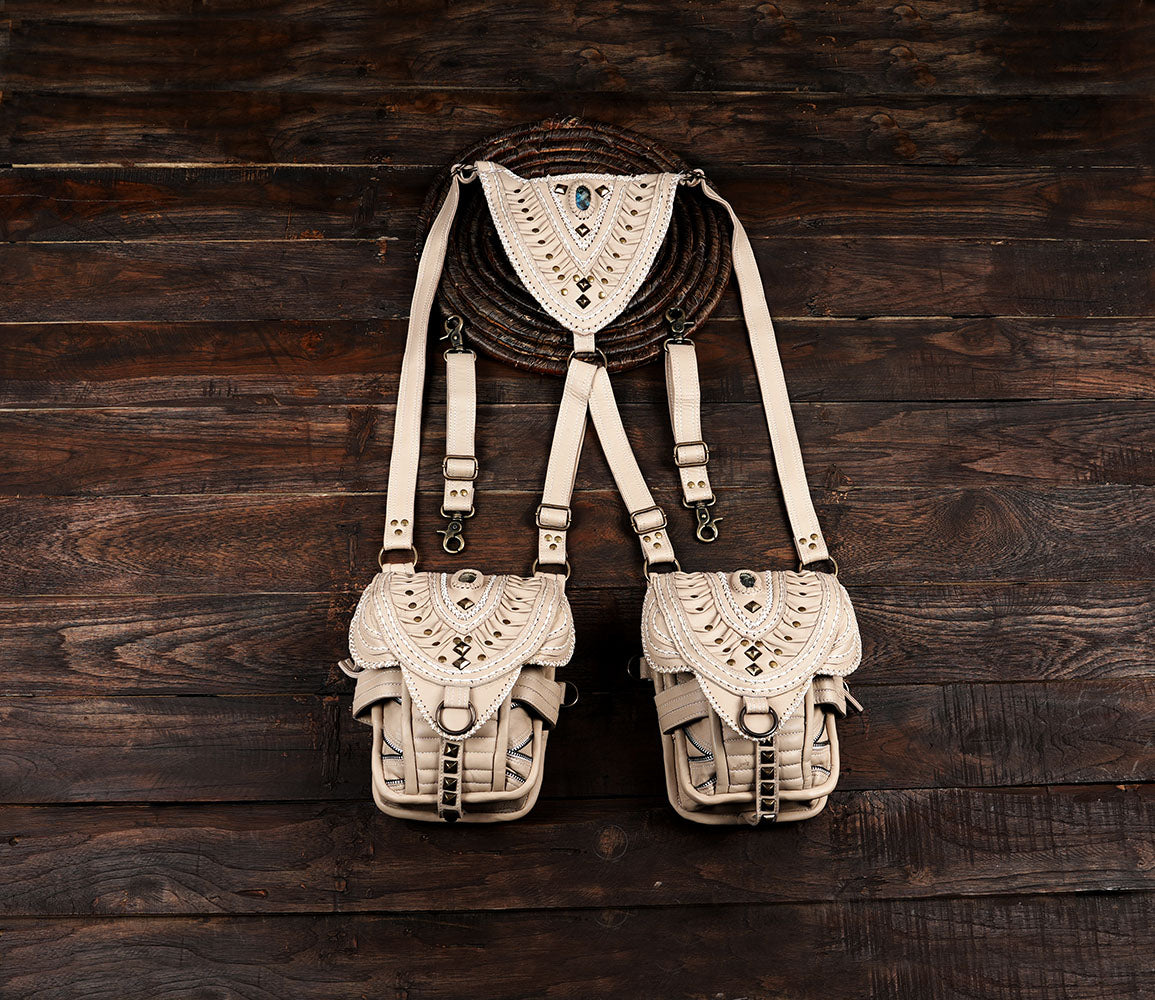 Off-white leather utility holster bag with two pockets and intricate embroidery on a dark wooden background.