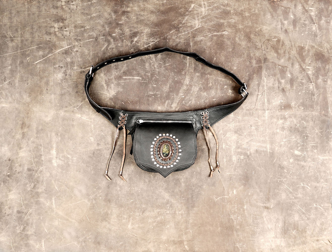 Black leather utility belt bag with a large central gemstone and lace-up details.