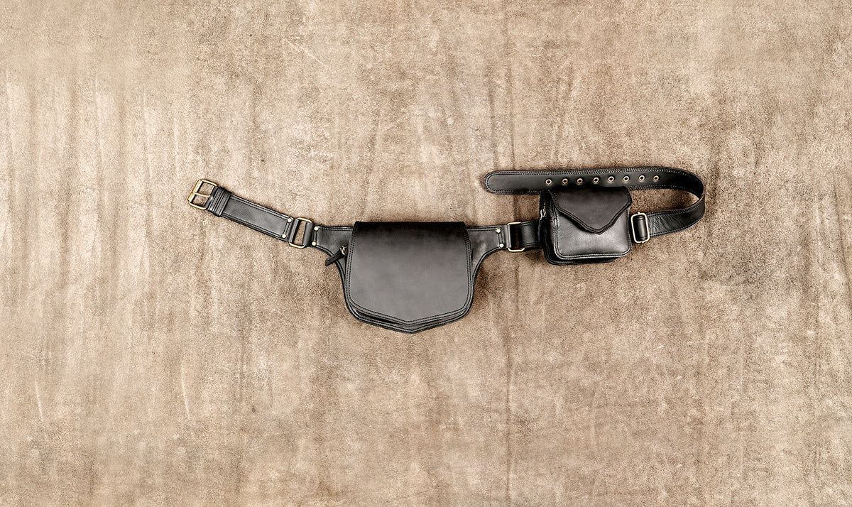 Black leather utility belt with dual pouches flat lay on a textured background   