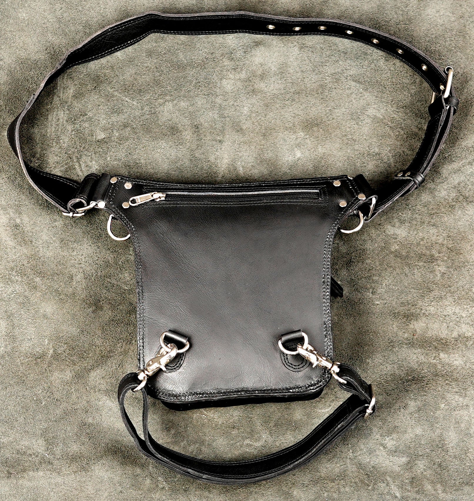 Adjustable black leather utility thigh bag with zipper closure and studs.