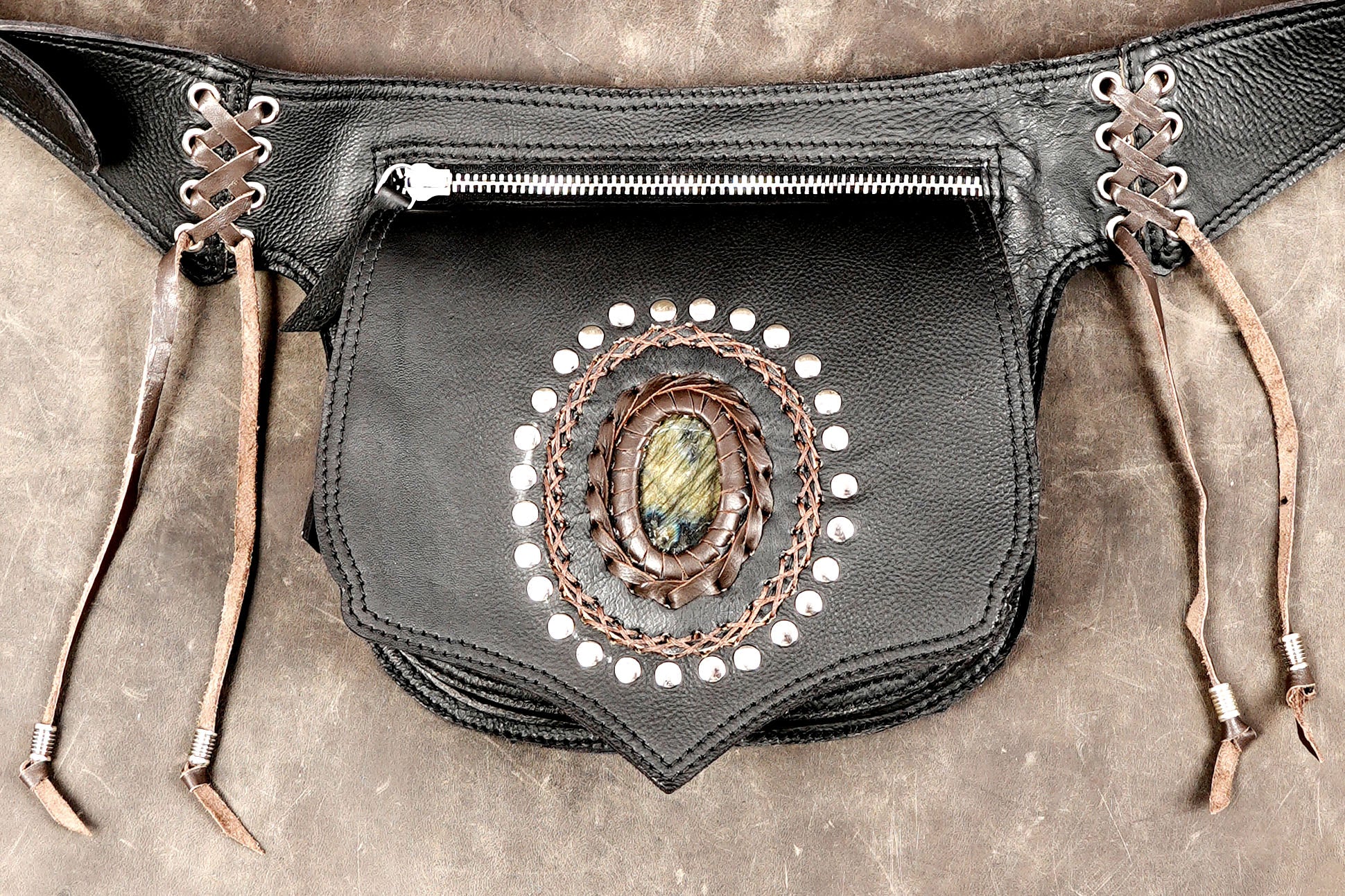 Festival hip bag in black leather with tribal-inspired silver studs and leather tassels.