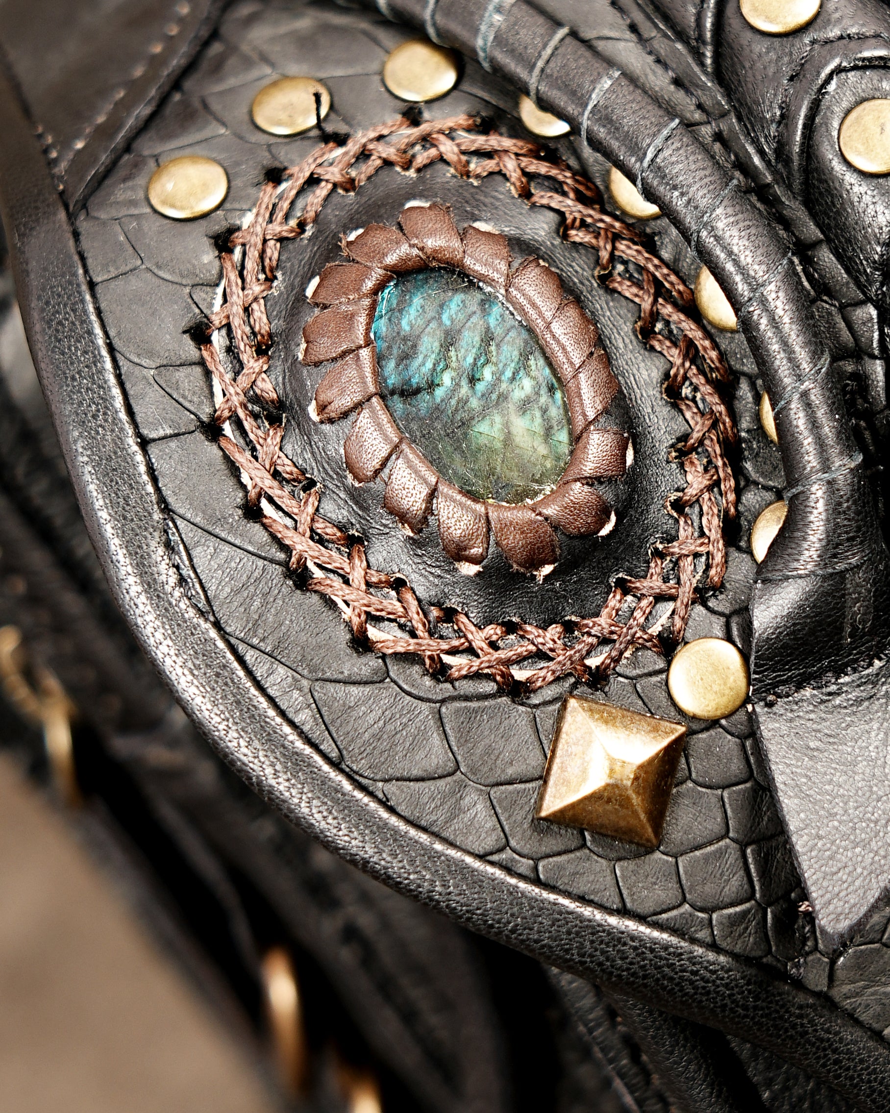 Black leather festival fanny pack with bohemian braided accents and brass buckles.