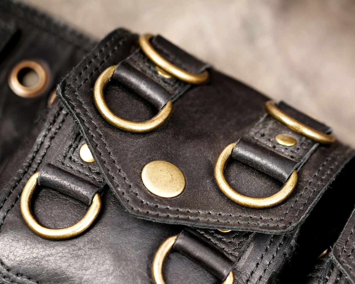 Black utility belt with stitched leather panels and brass-tone D-rings.